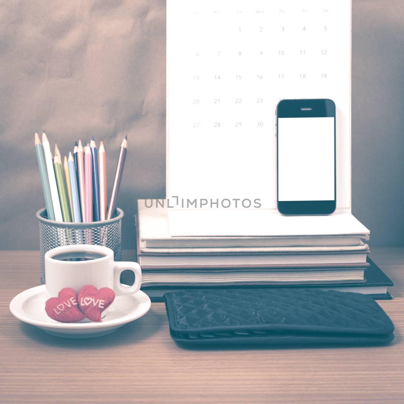 office desk : coffee with phone,wallet,calendar,heart,color pencil box,stack of book,heart on wood background vintage style