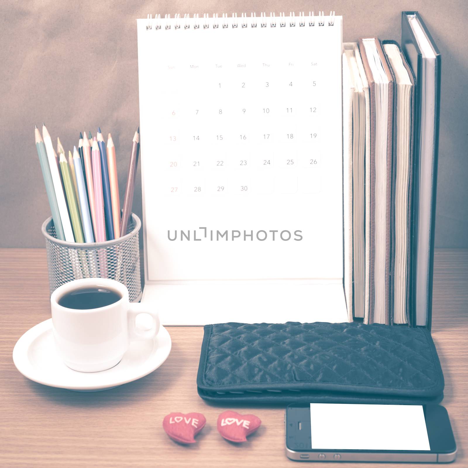 office desk : coffee with phone,wallet,calendar,heart,color pencil box,stack of book,heart on wood background vintage style