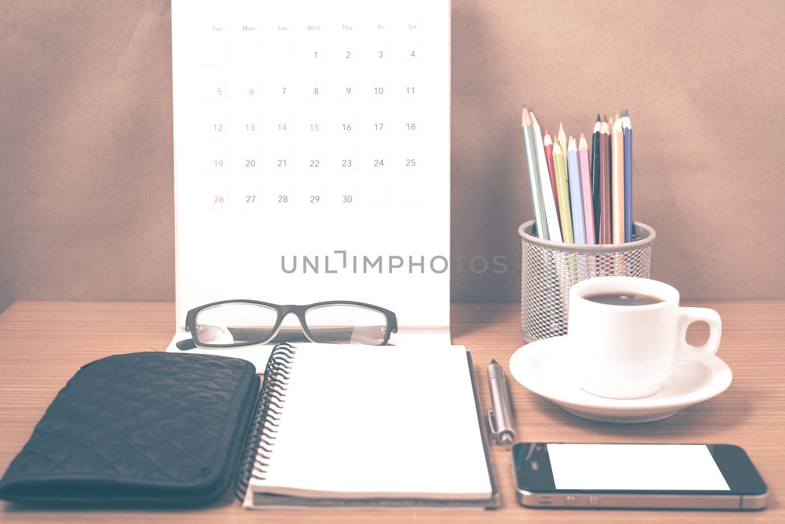 office desk : coffee with phone,wallet,calendar,heart,notepad,eyeglasses,color pencil box on wood background vintage style