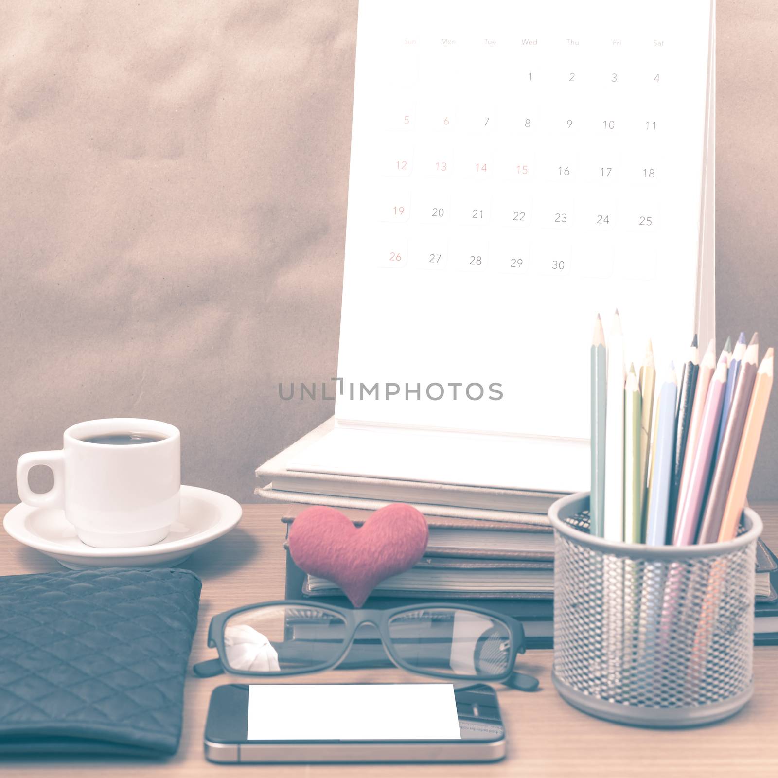 office desk : coffee with phone,wallet,calendar,color pencil box,stack of book,heart,eyeglasses on wood background vintage style