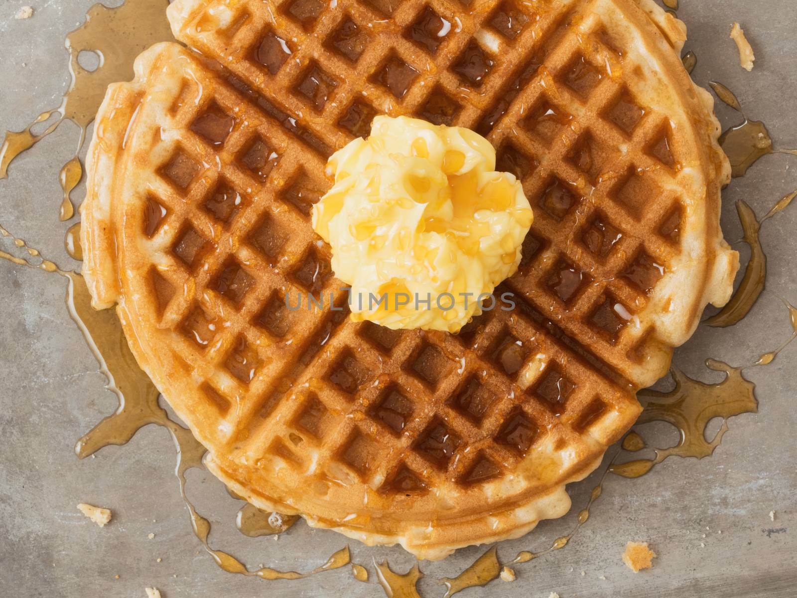 close up of rustic traditional waffle with butter and maple syrup