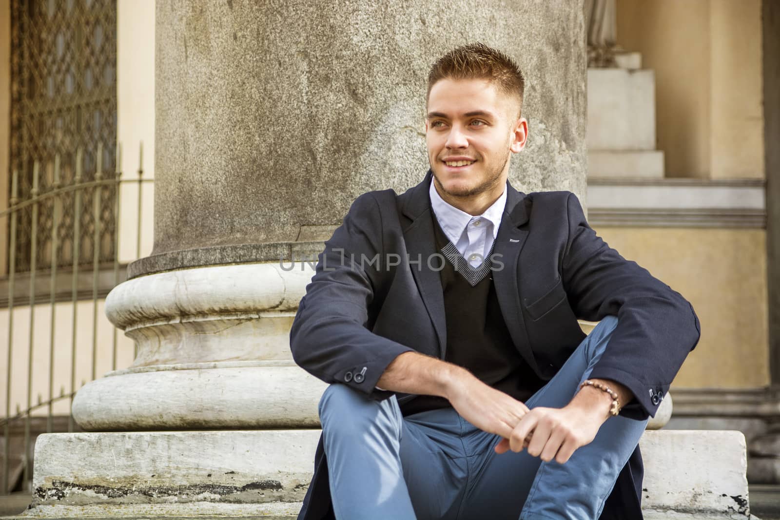 Handsome young man outdoor wearing jacket and shirt standing by historic building in European city. Turin, Italy