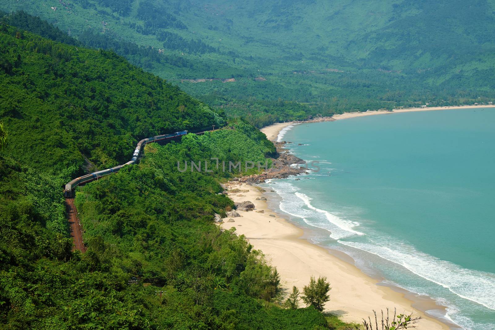 Panorama scene of Lang Co beach, Hue from Hai Van mountain pass at Da Nang, Viet Nam. Amazing landscape of train moving on railway at seaside, nice view of nature with green forest, wave on sea