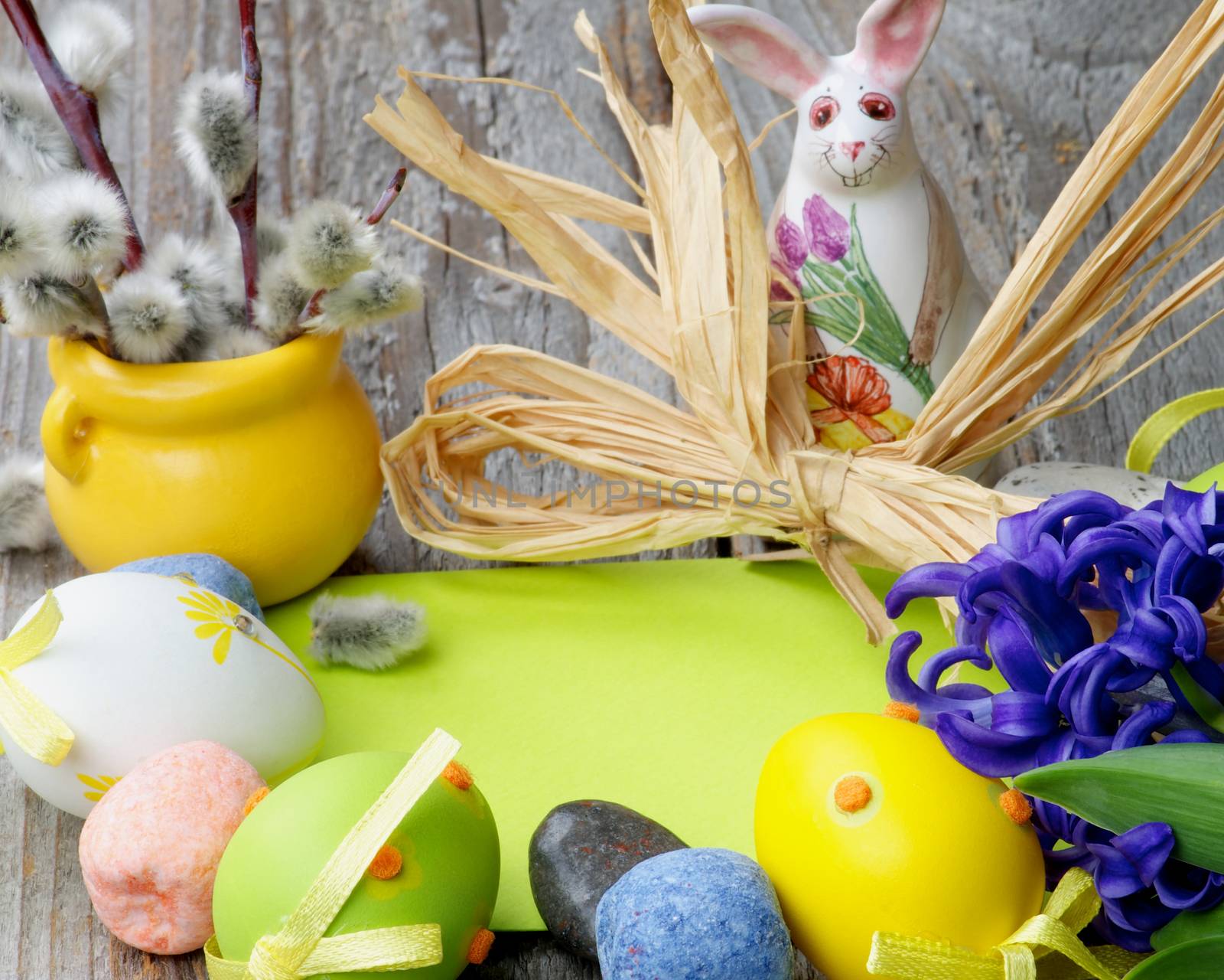 Easter Greeting Concept with Pussy-Willow, Ceramic Bunny, Colored Stones, Crocus, Easter Eggs and Empty Green Place to Congratulations closeup on Wooden background