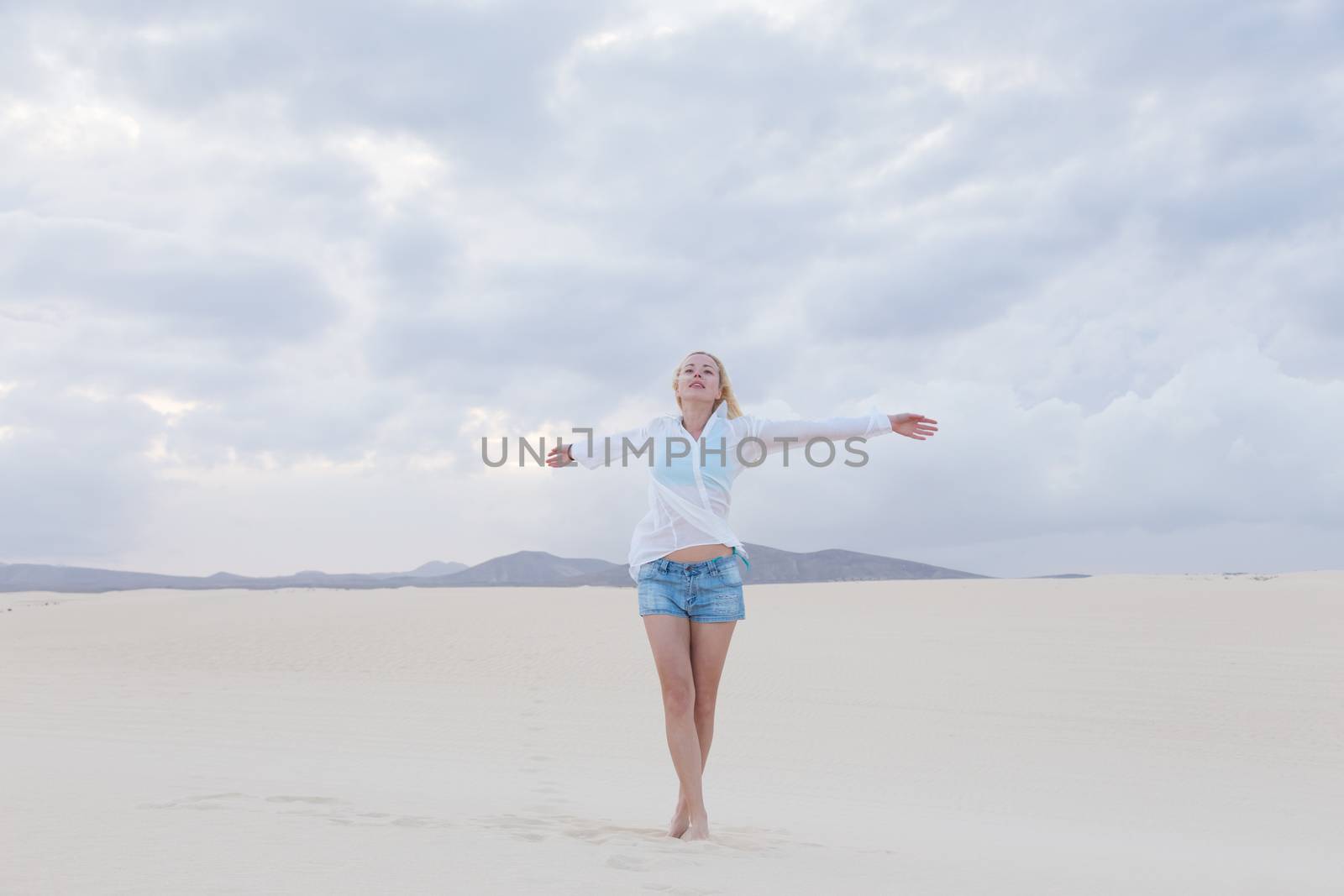 Relaxed woman enjoying freedom feeling happy at beach in the morning. Serene relaxing woman in pure happiness and elated enjoyment with arms outstretched. Copy space.