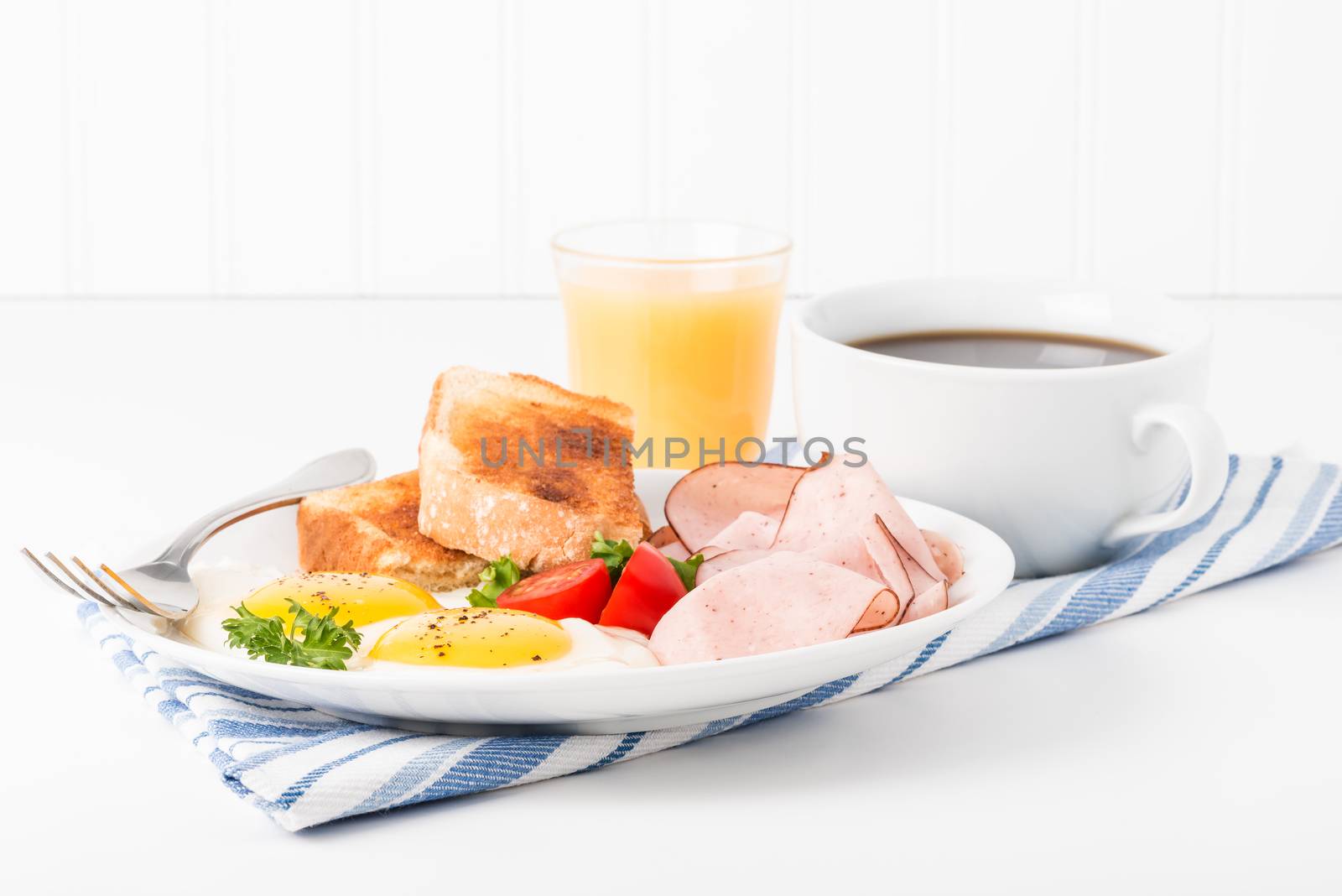Eggs sunny side up served with ham, coffee and toast.