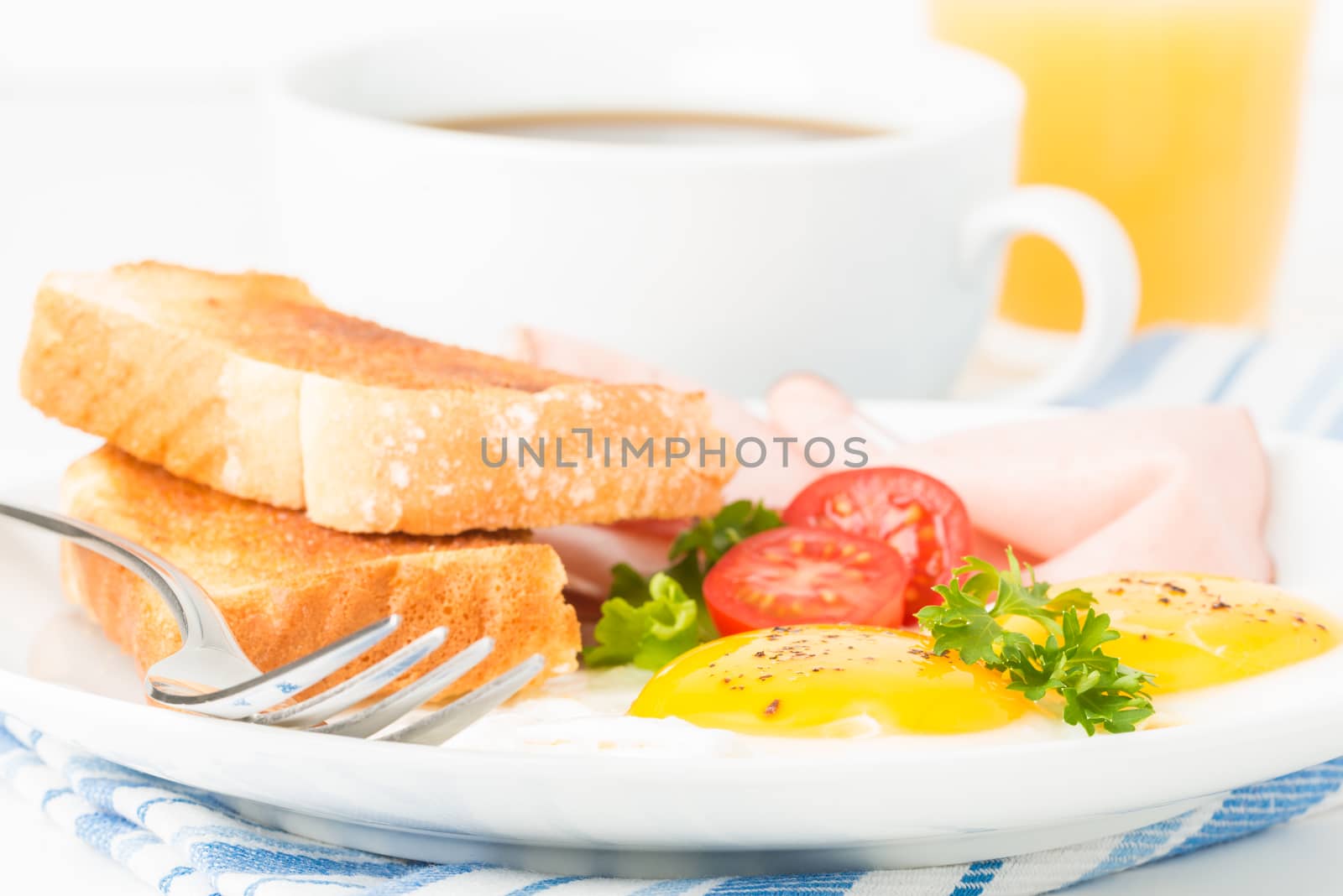 Eggs sunny side up with ham and toast photographed closeup.