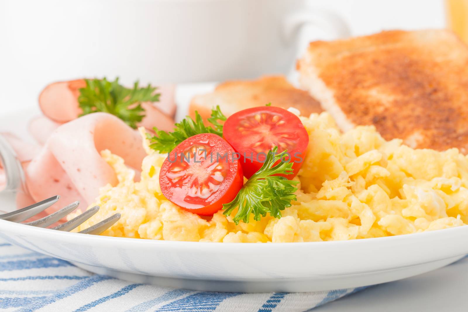 Scrambled eggs and ham with fresh tomatoes photographed closeup.