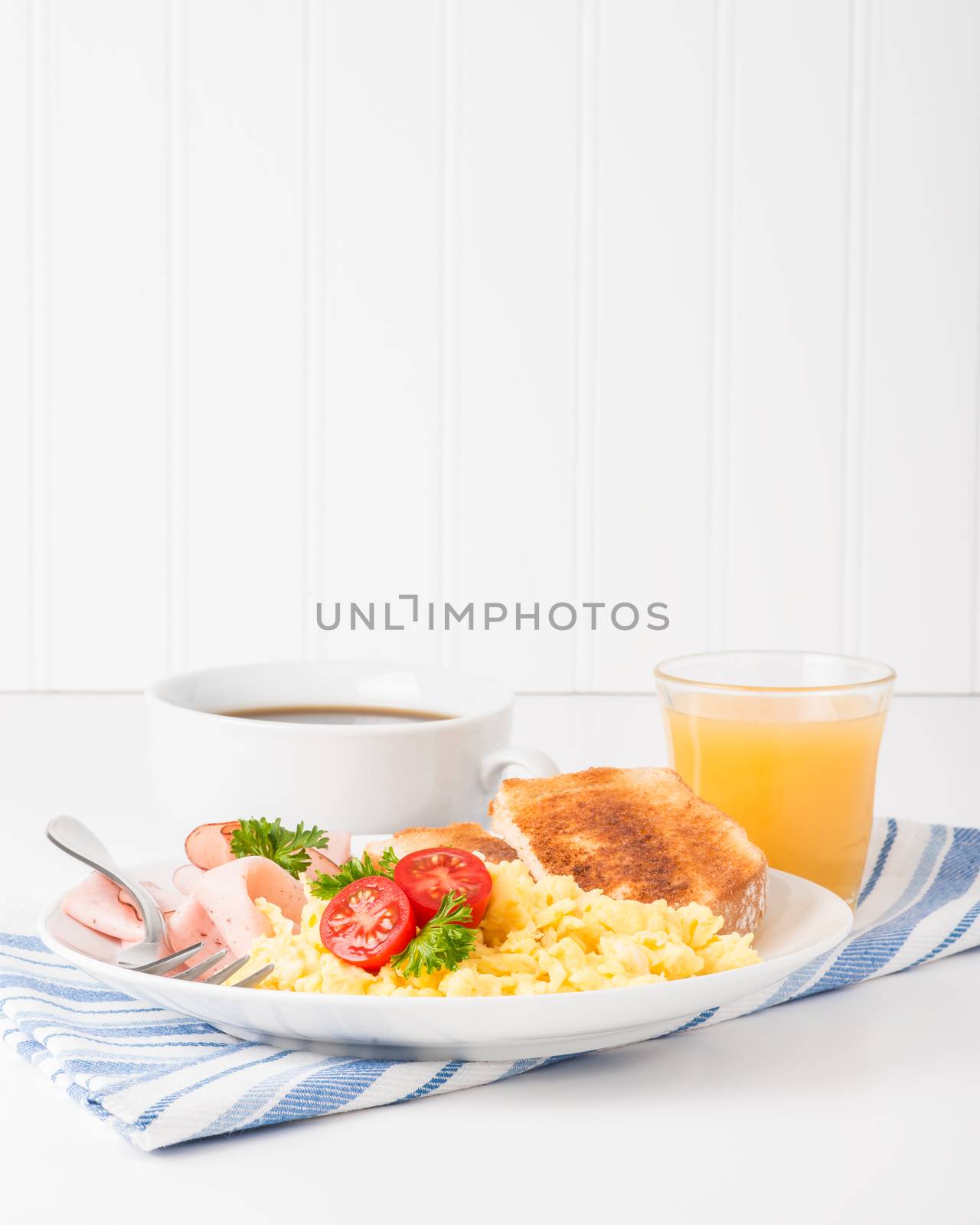 Portrait view of a plate of scrambled eggs and ham.