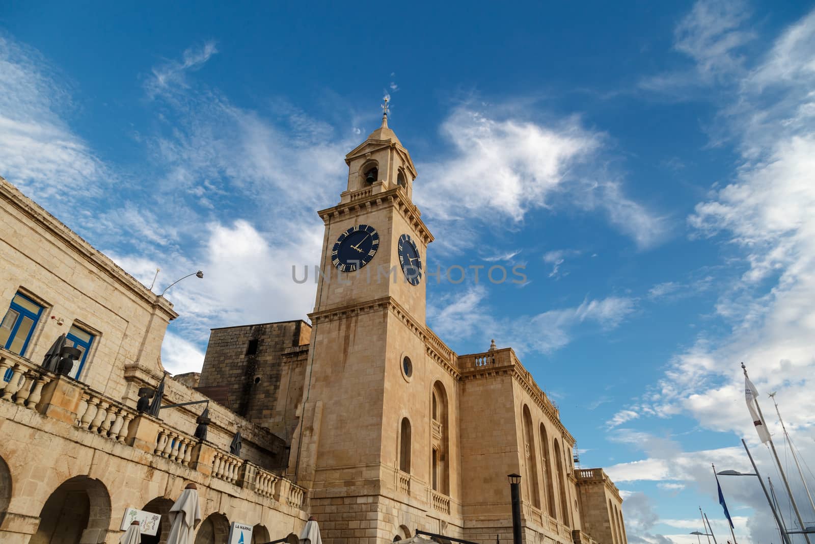 VALETTA, MALTA - NOVEMBER 2, 2015 : View of a church in Valletta Malta with limestone belfry clock tower, on cloudy blue sky background.