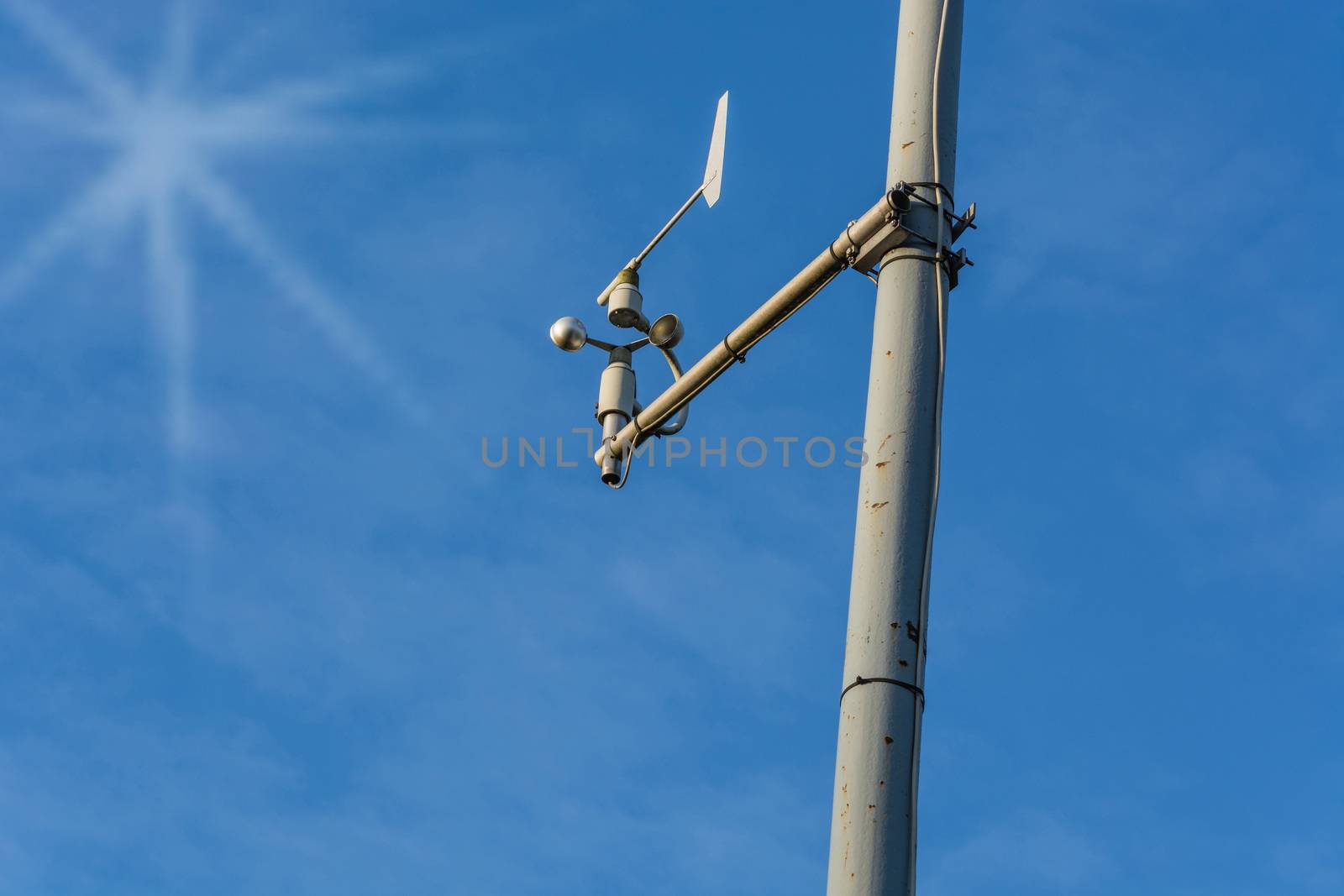 Weather station with anemometer on blue sky.