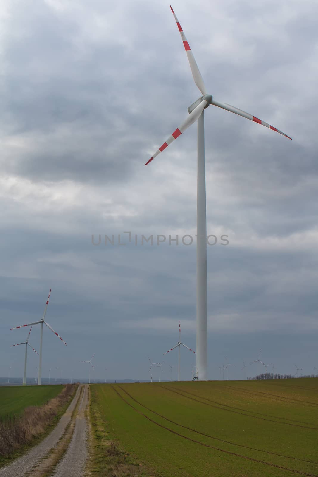 Wind turbine and an early spring field in Berg, Austria. Rainy cloudy sky.