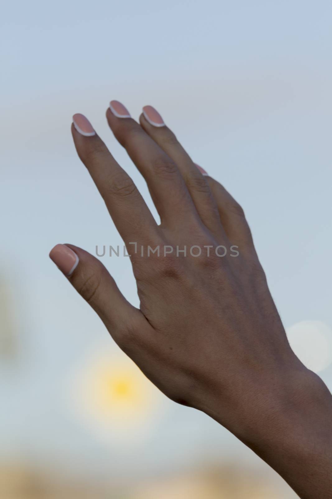 arm girls with beautiful manicure on a background of the blue sky