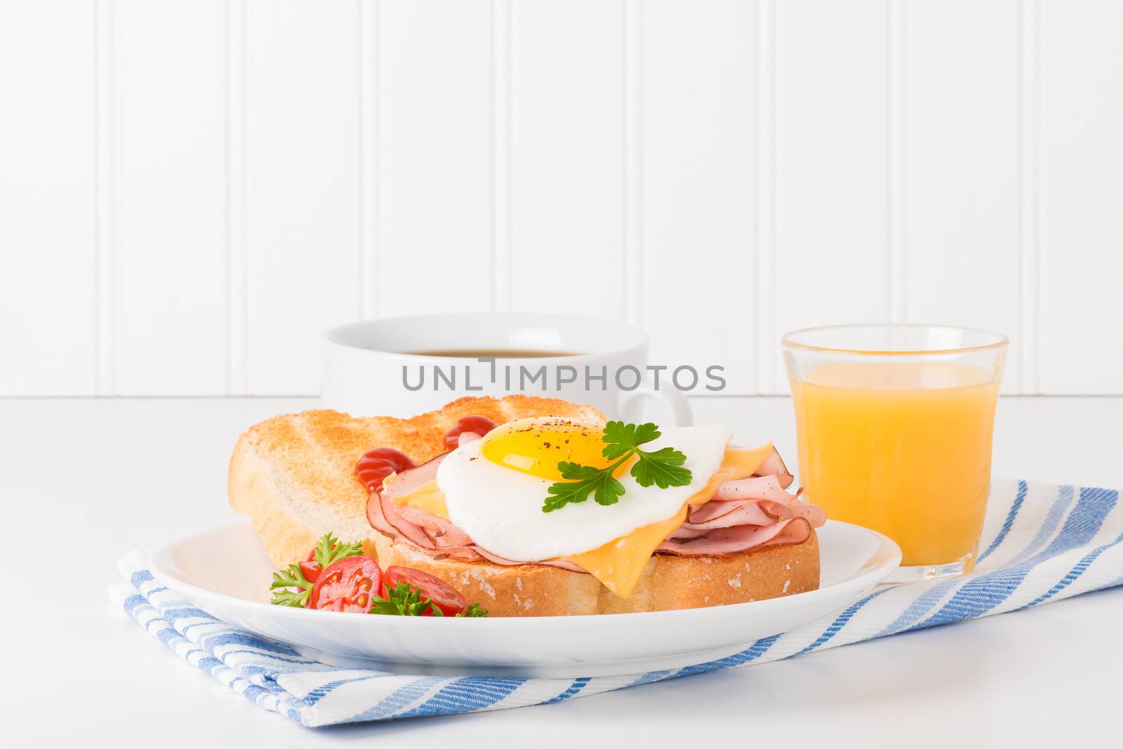 Delicious sandwich of fried egg, ham and cheese served with coffee and juice.