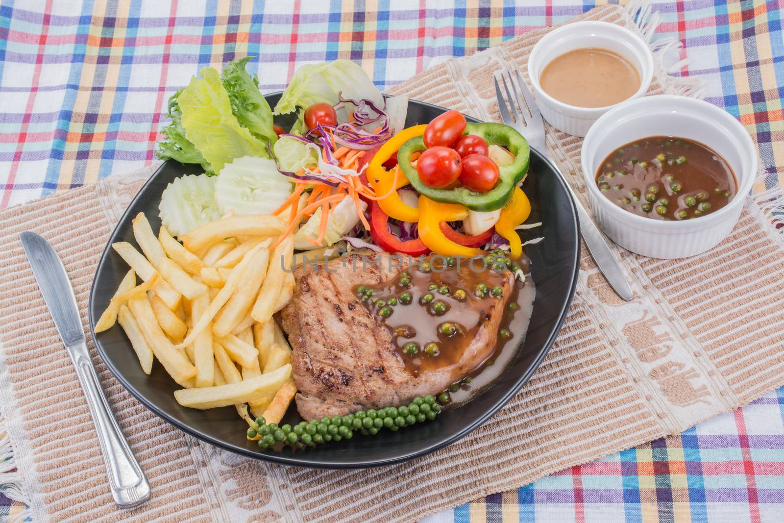Pork steak with brown pepper sauce served with potato chips and salad with sesame japanese dressing.