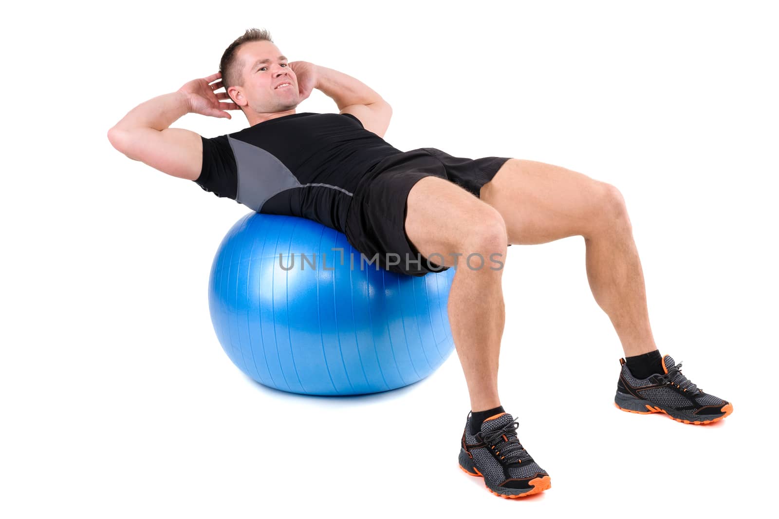 Young man shows finishing position of Abdominal Fitball Workout, isolated on white