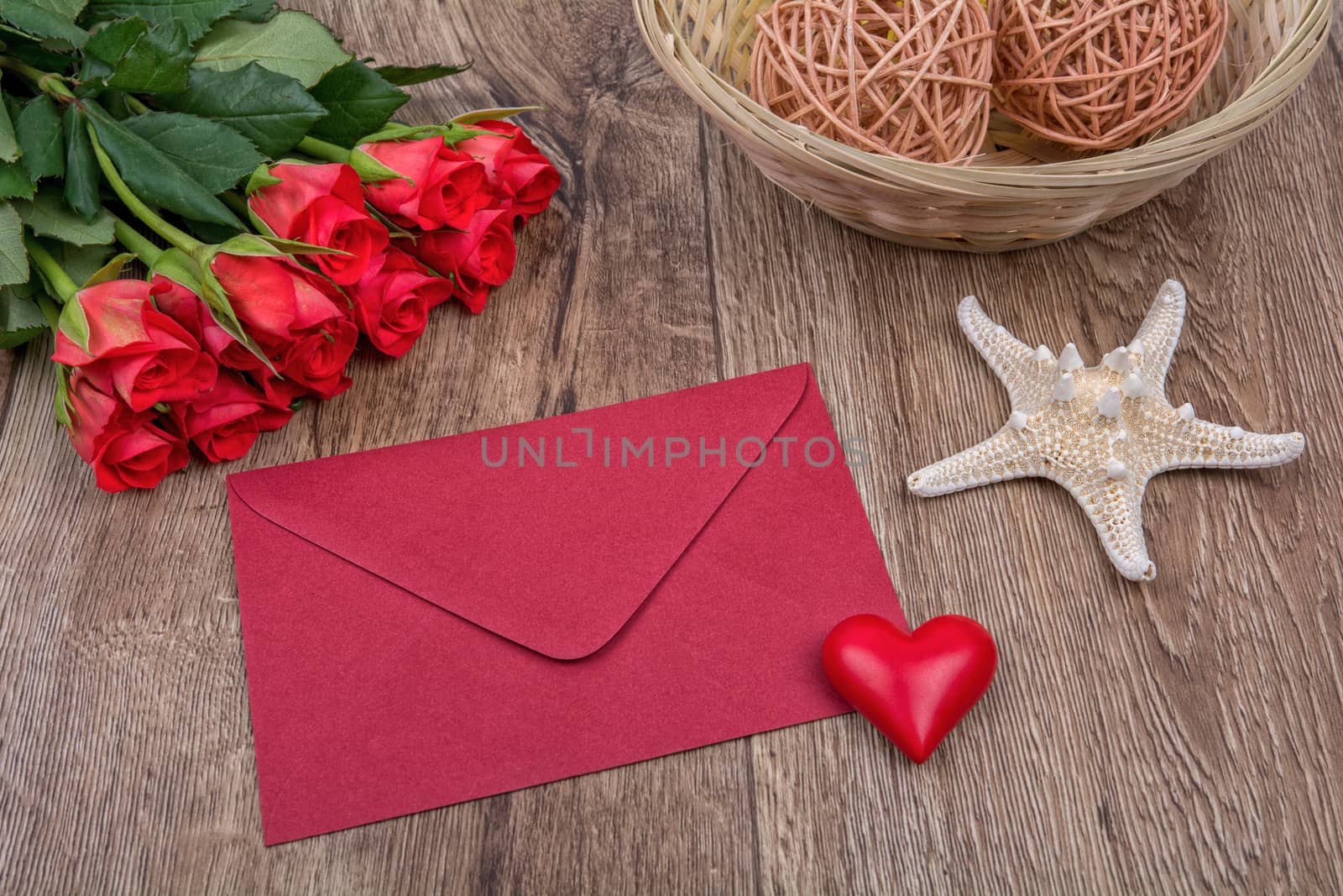 Red envelope, red roses and white starfish on a wooden background