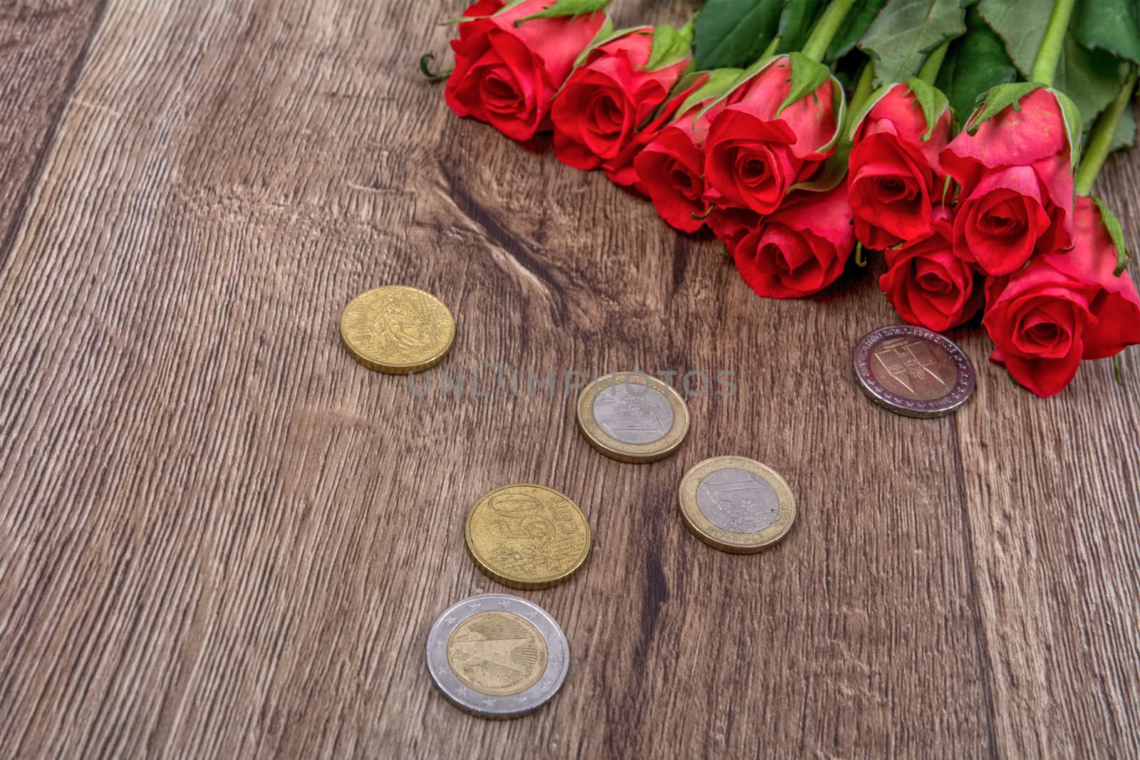 Euro coins and red roses on a wooden background
