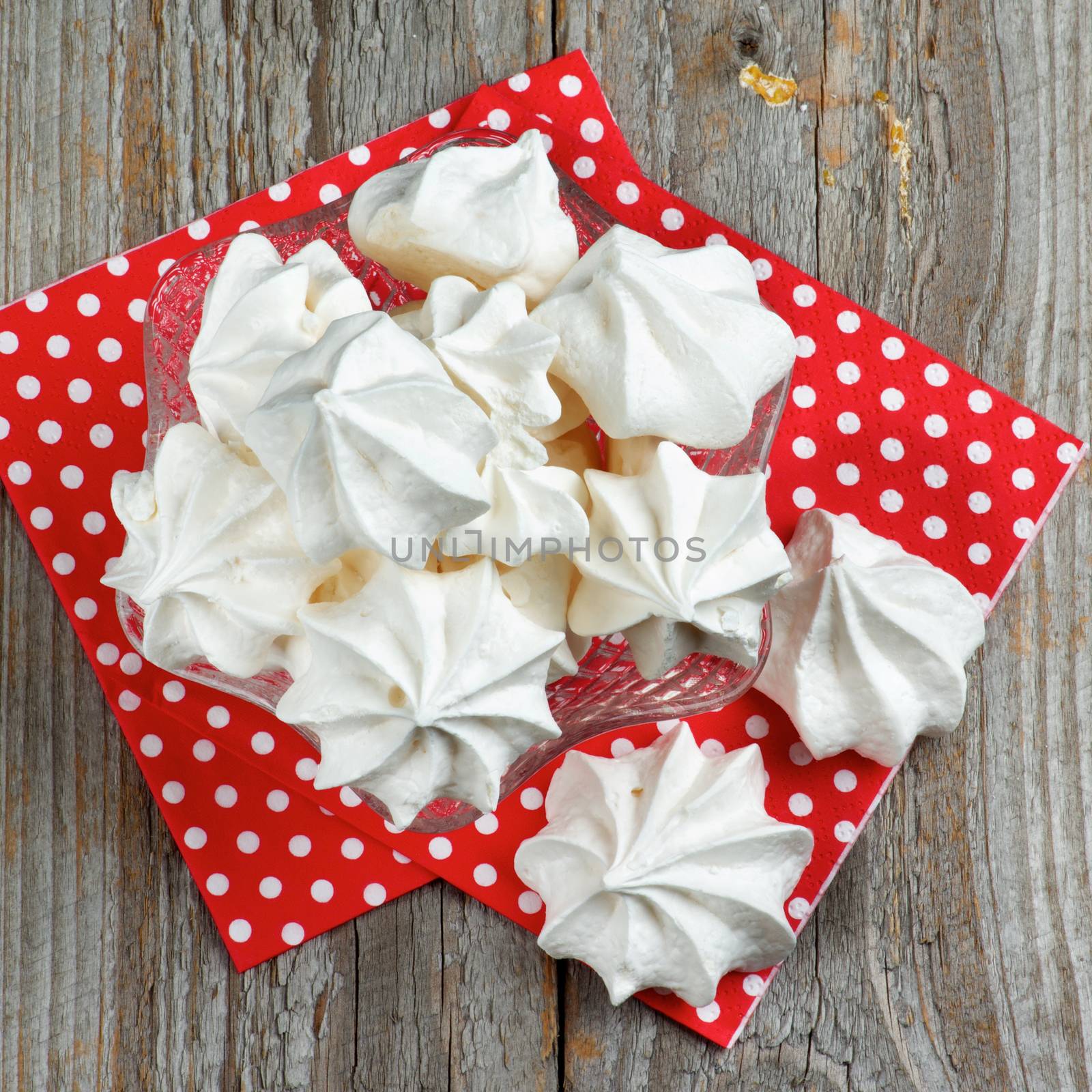 White Meringue Cookies in Dessert Vase on Red Polka Dot Napkin closeup. Top View on Wooden background