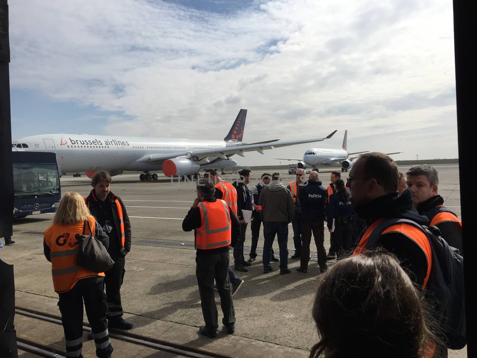 BELGIUM, Brussels: Ground crew members stand outside a hangar at Zaventem airport on March 22, 2016, after terrorist bombings killed at least 30 people, both at the airport and at Maelbeek metro station.Pictures show hundreds of passengers stranded after the attack.