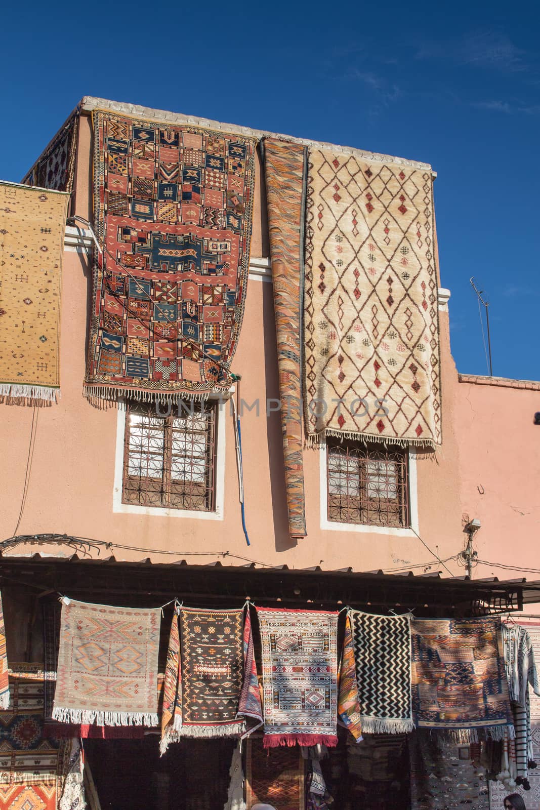 House with a carpets shop. Carpets displayed hanging from the roof. Bright blue sky. Medina of Marrakesh, Morocco.