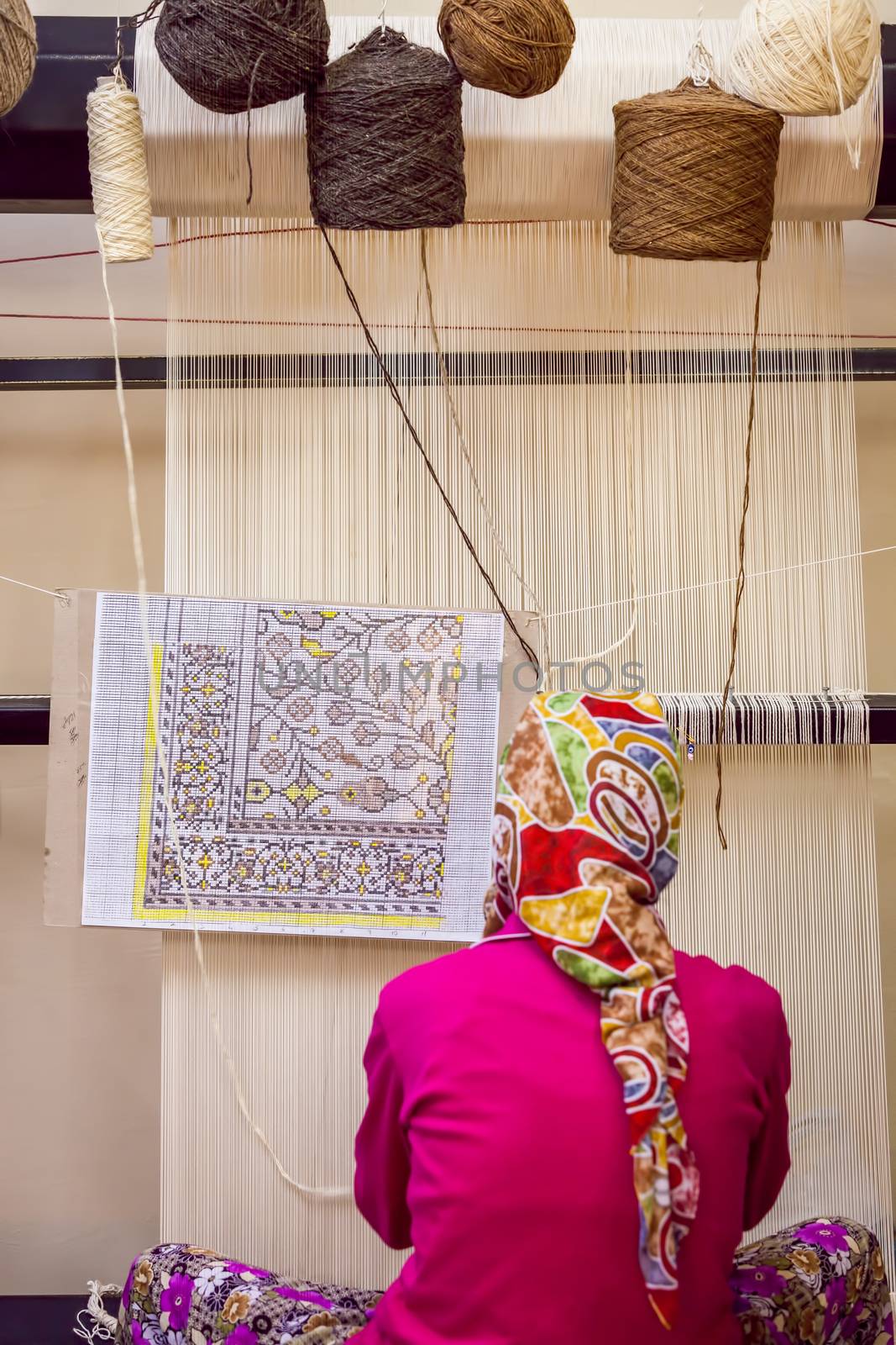 SELCUK, TURKEY – APRIL 21: Woman works at loom weaving traditional carpet on April 21, 2012 in Selcuk, Turkey.