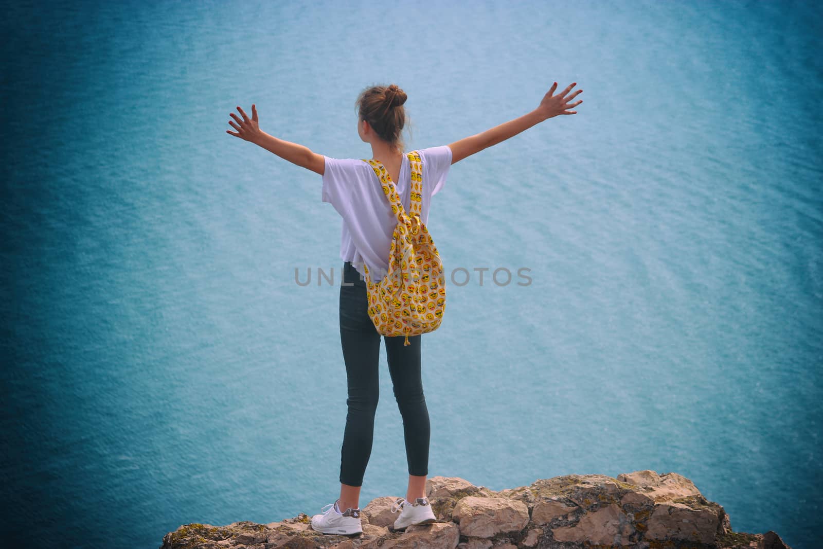 La Turbie, France - March 22, 2016: Freedom Concept. Free Happy Young Woman with a Backpack with Smileys Enjoying Nature. Mediterranean Sea in the Background