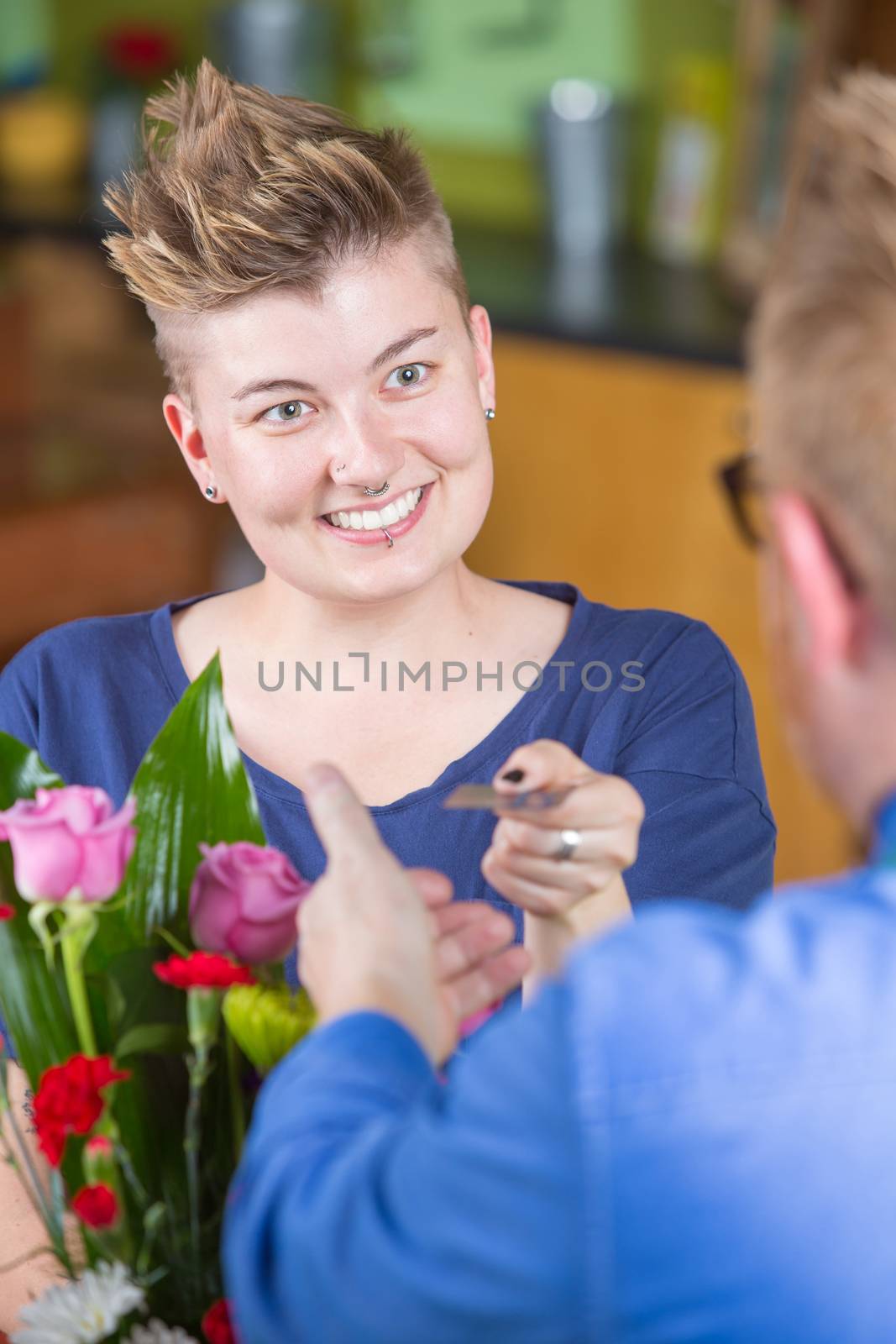 Smiling female customer in flower shop using credit