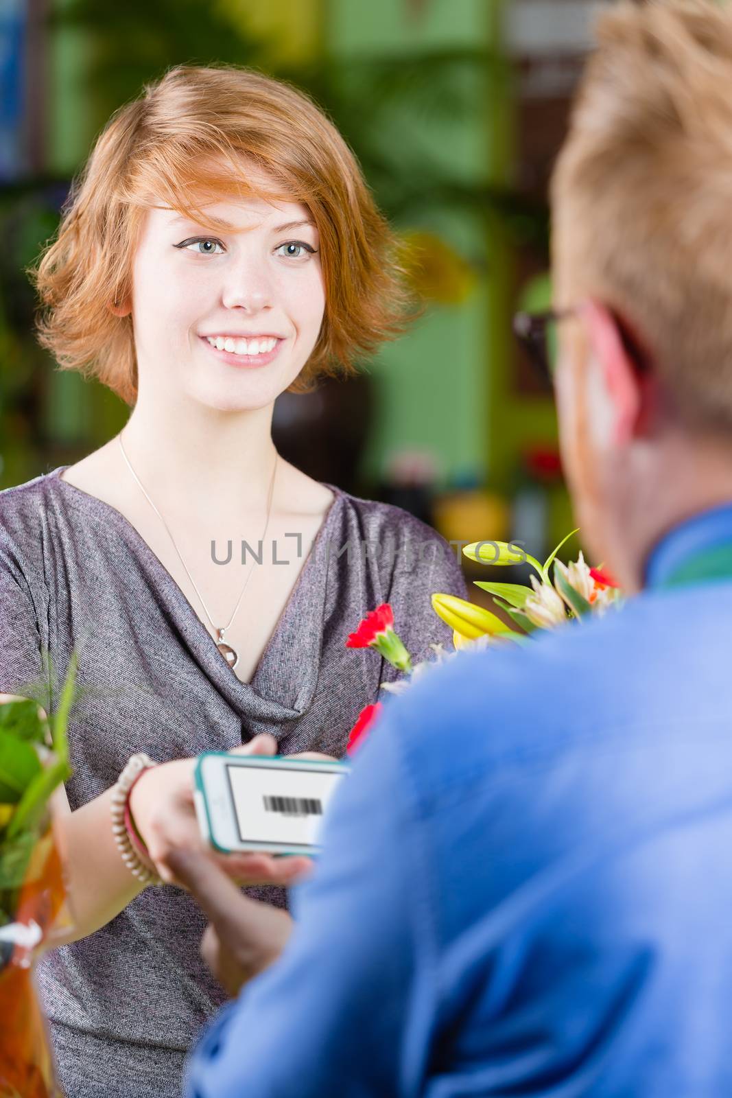 Smiling customer in a busy flower shop using electronic coupon