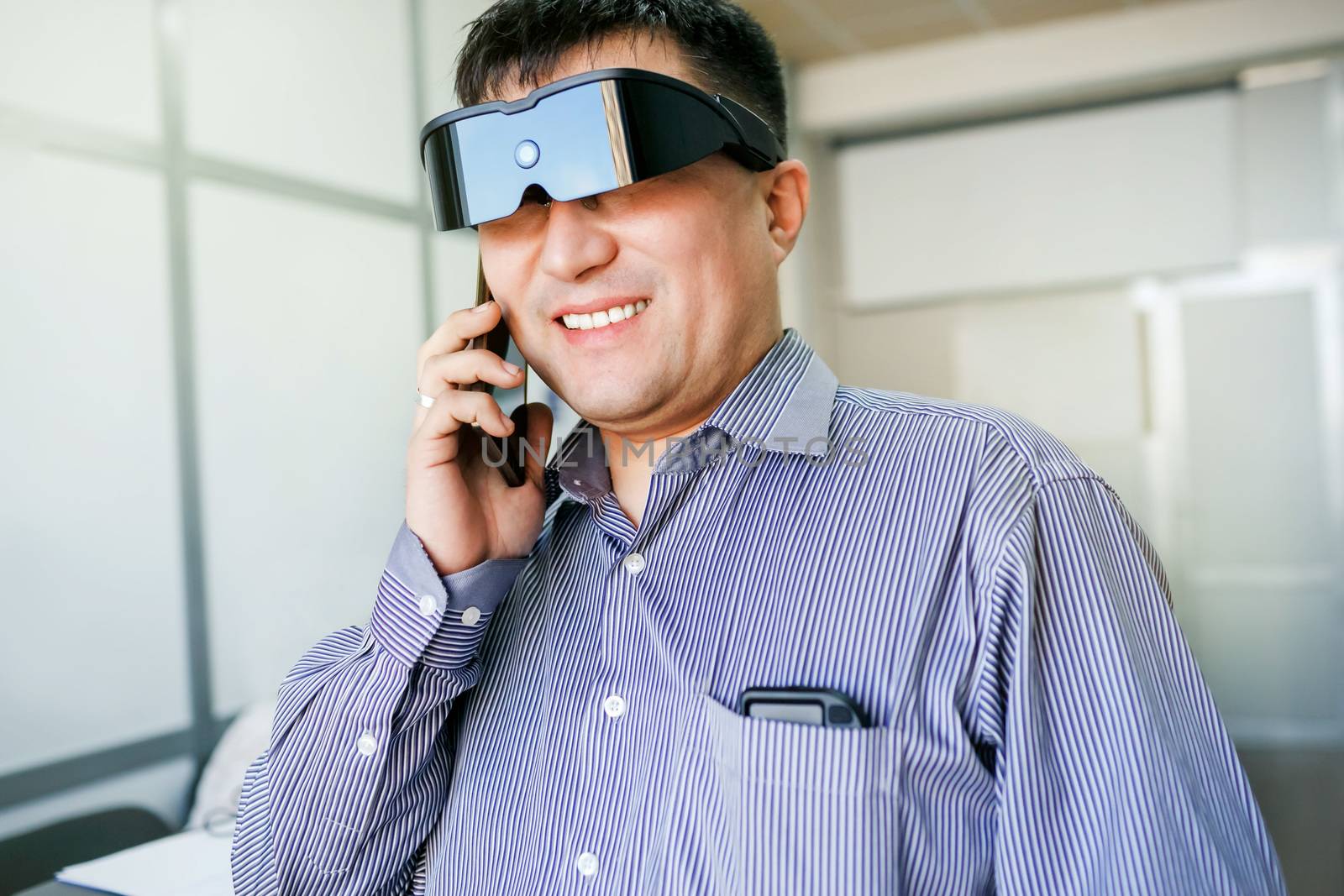 The man with glasses of virtual reality talking on the phone inside the office.