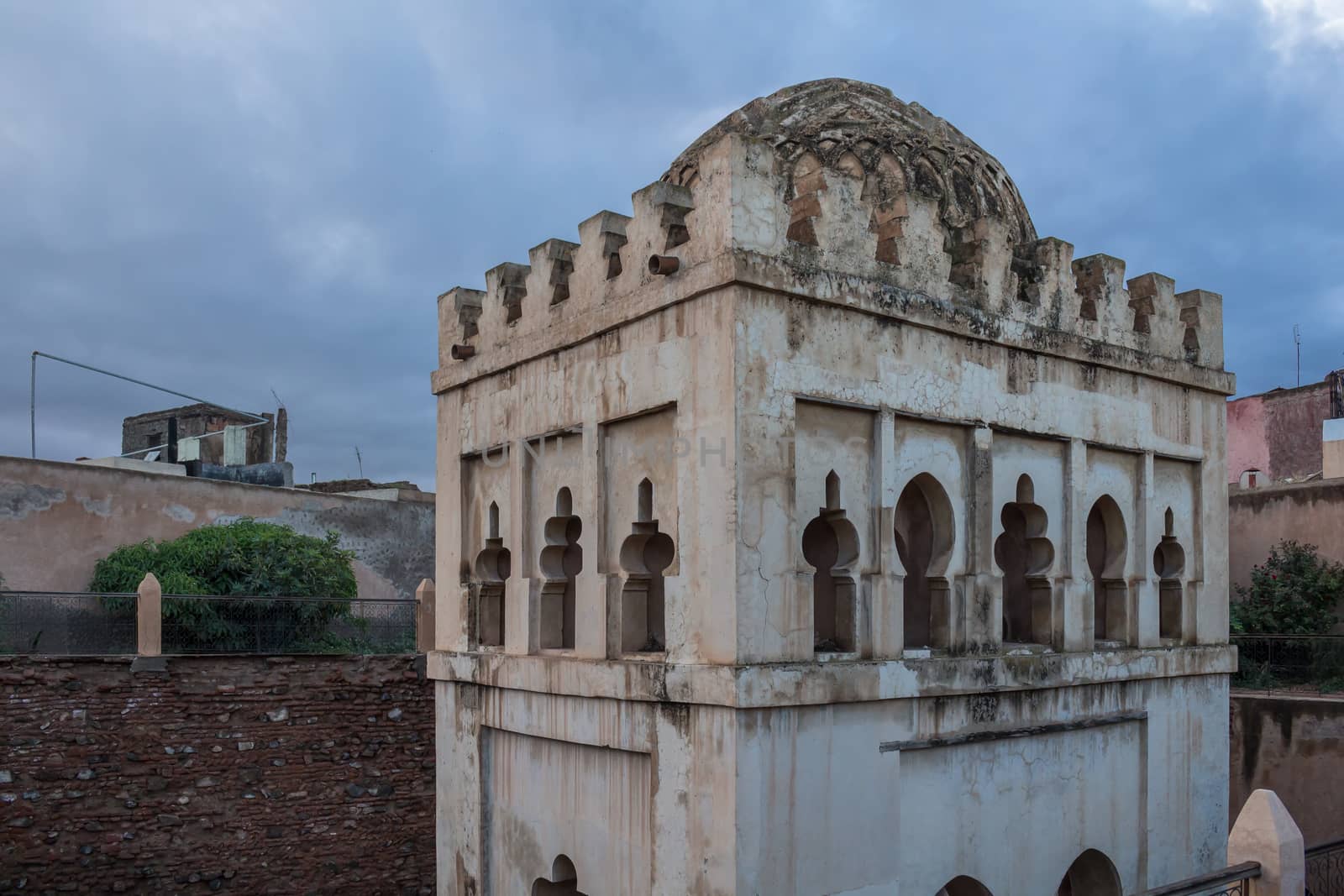 Tower built in traditional arabian style with a dome on the top, surrounded by residential houses. Early morning during dawn.