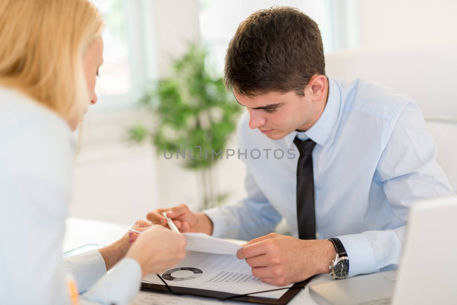 Businessman discussing and looking at document with female colleague in the office. Selective focus.