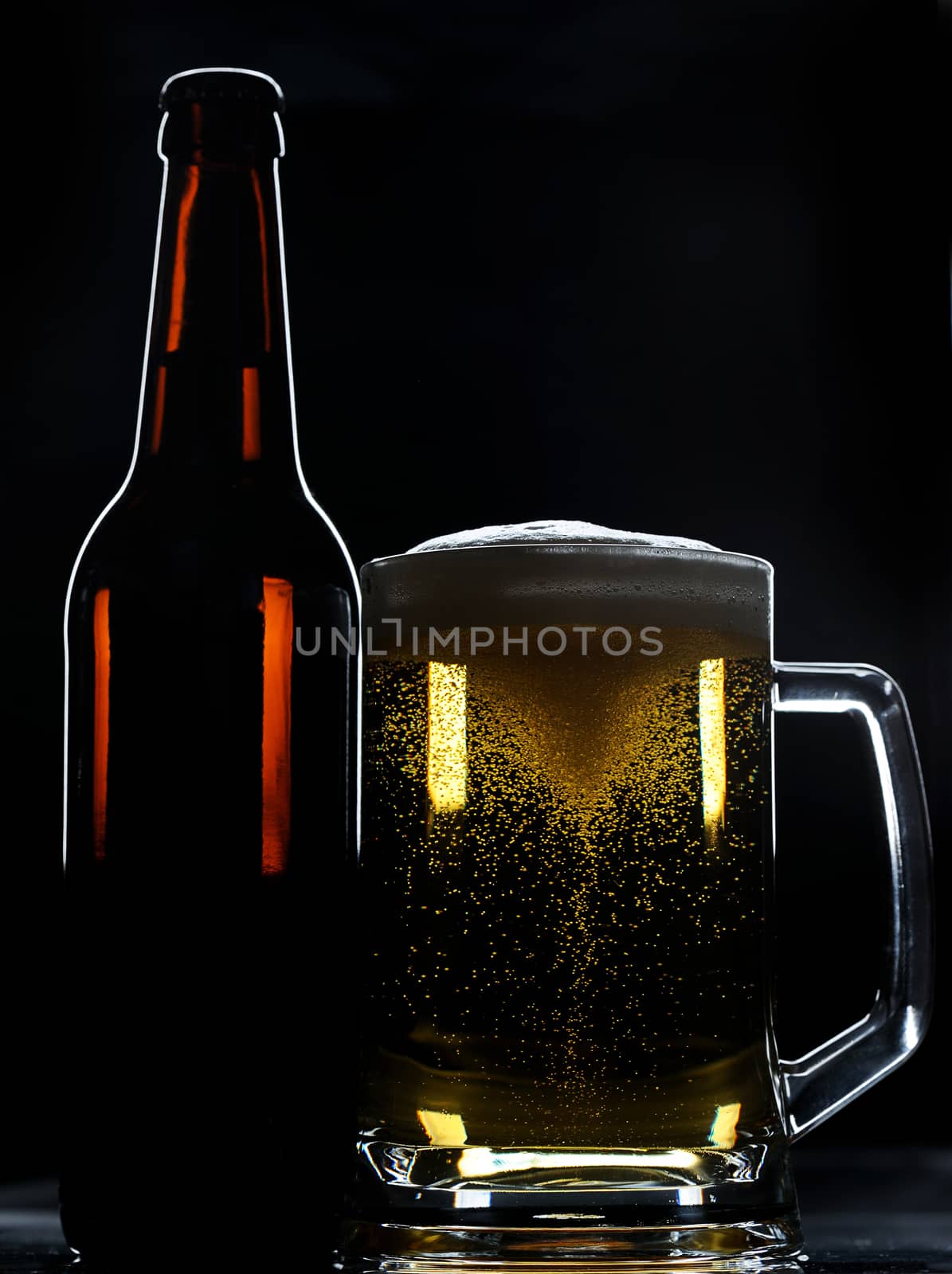 beer bottle and glass with spinning bubbles on black background