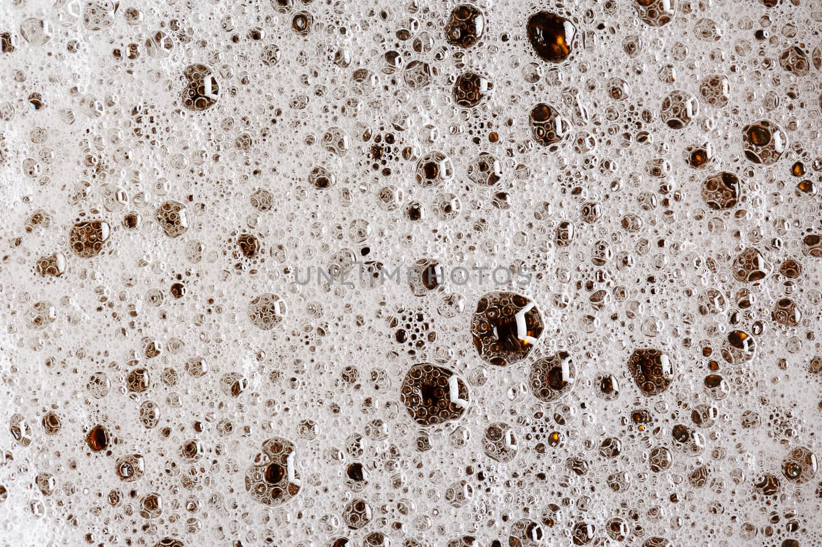 close up of bubbles on beer foam in glass