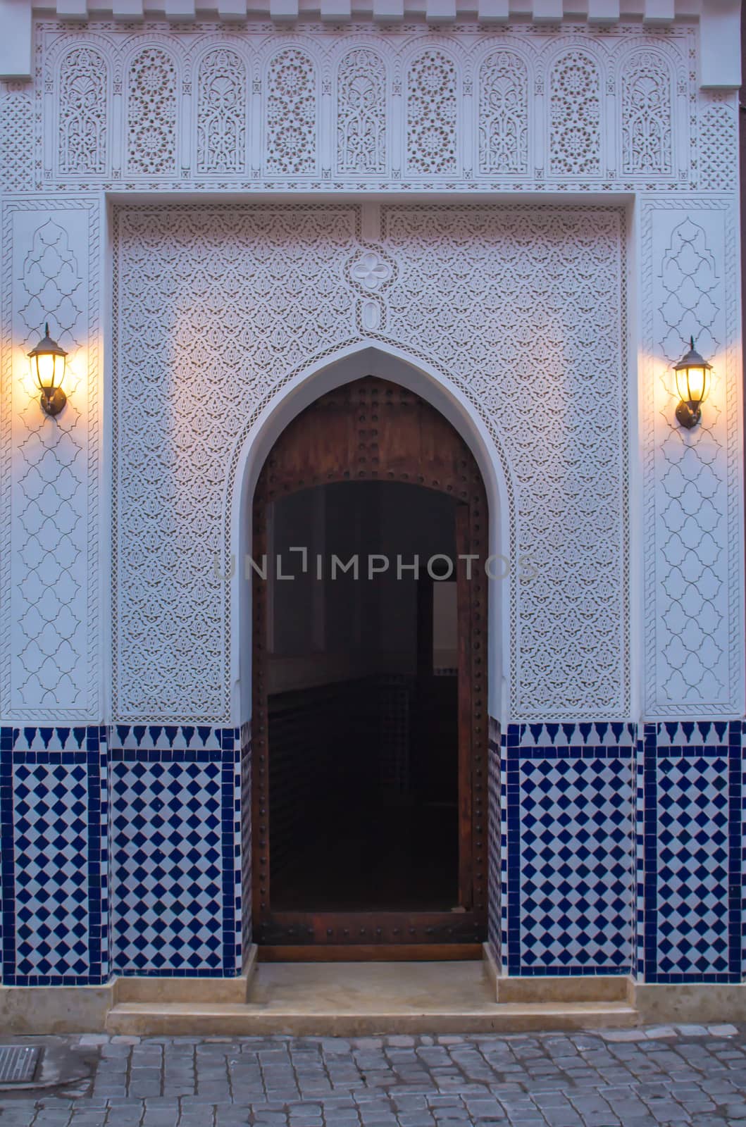 Traditional gate in the medina of Marrakesh during dawn. Beauty of the details of the decoration of the gate. Soft light of the lanterns.