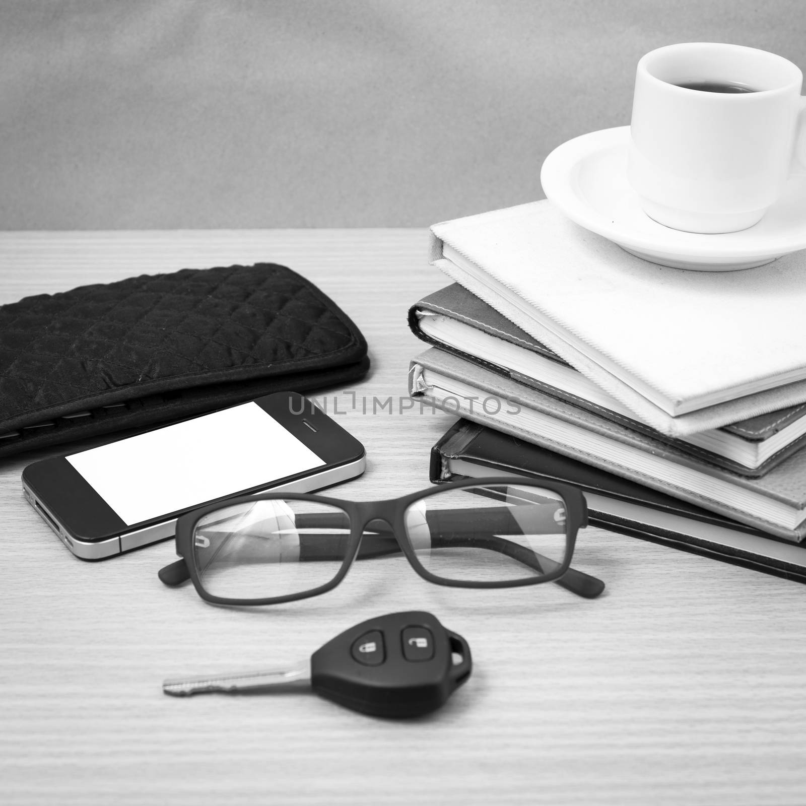 coffee and phone with stack of book,car key,eyeglasses and wallet on wood background black and white color