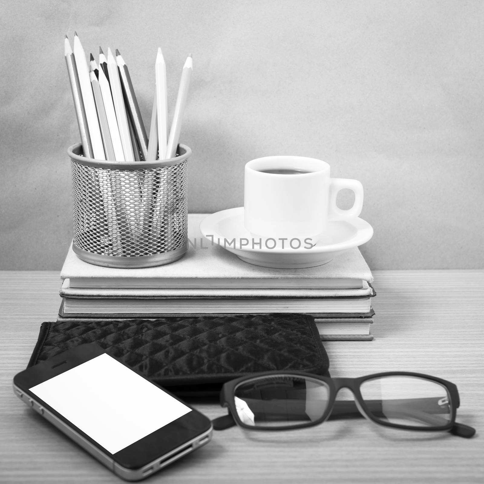 office desk : coffee with phone,stack of book,eyeglasses,wallet,color pencil box on wood background black and white color