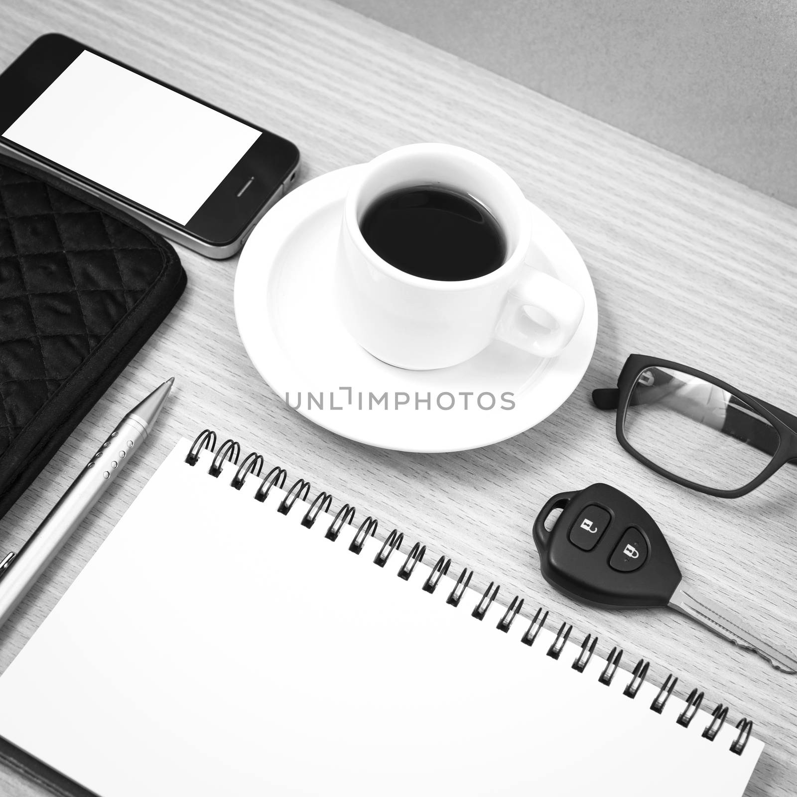 coffee and phone with notepad,car key,eyeglasses and wallet on wood table background black and white color