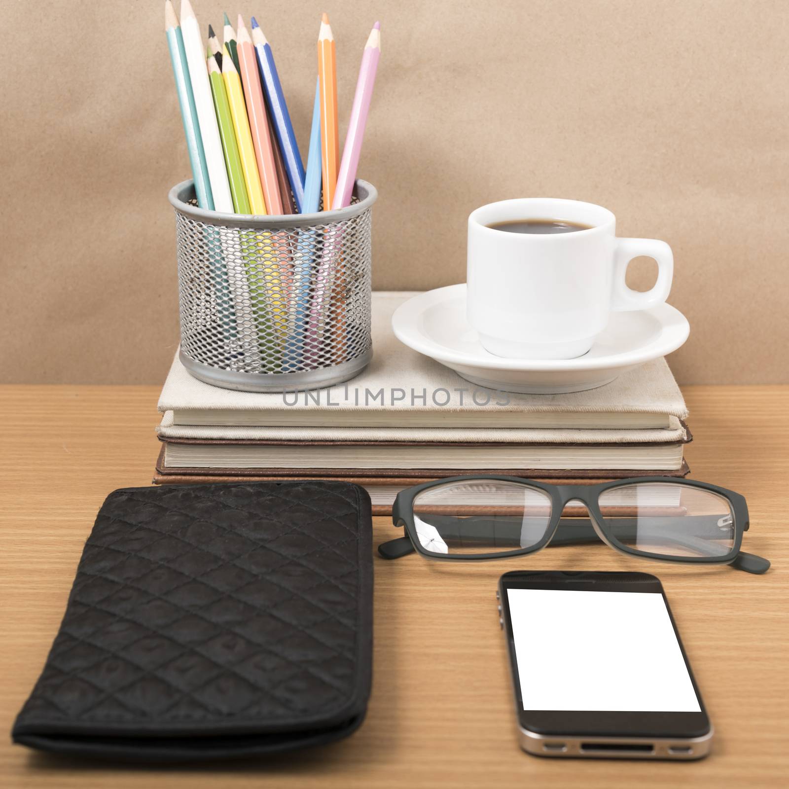 office desk : coffee with phone,stack of book,eyeglasses,wallet,color pencil box on wood background