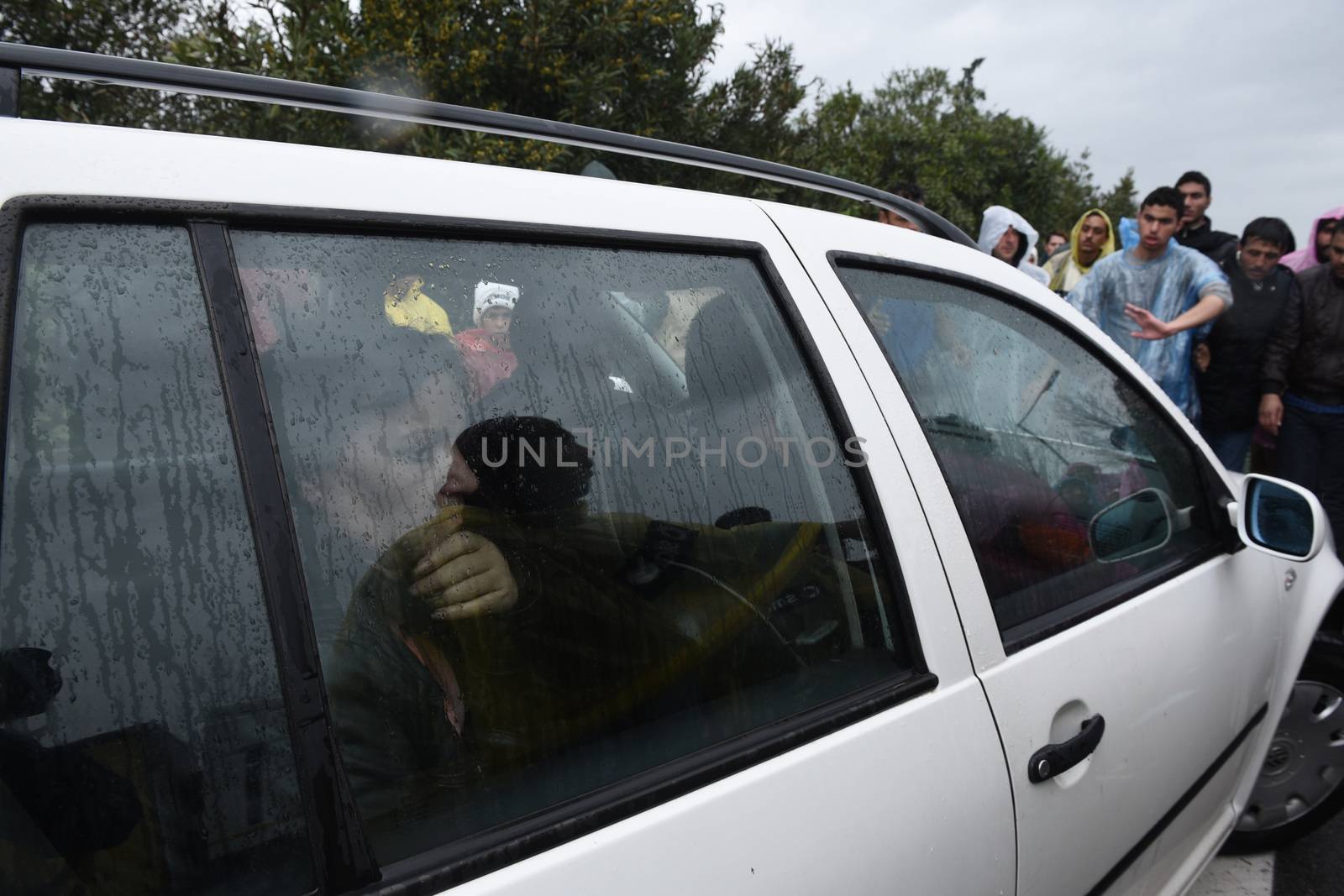 GREECE, Idomeni: A woman looks out from a car as migrants block the road on March 23, 2016.Refugees and migrants blocked the main highway road near the northern Greek village of Idomeni at the Greek-Macedonian border, cutting off traffic between Greece and Macedonia, on March 23, 2016. People demonstrated demanding for the border to open, in order to continue their trip to northern Europe.