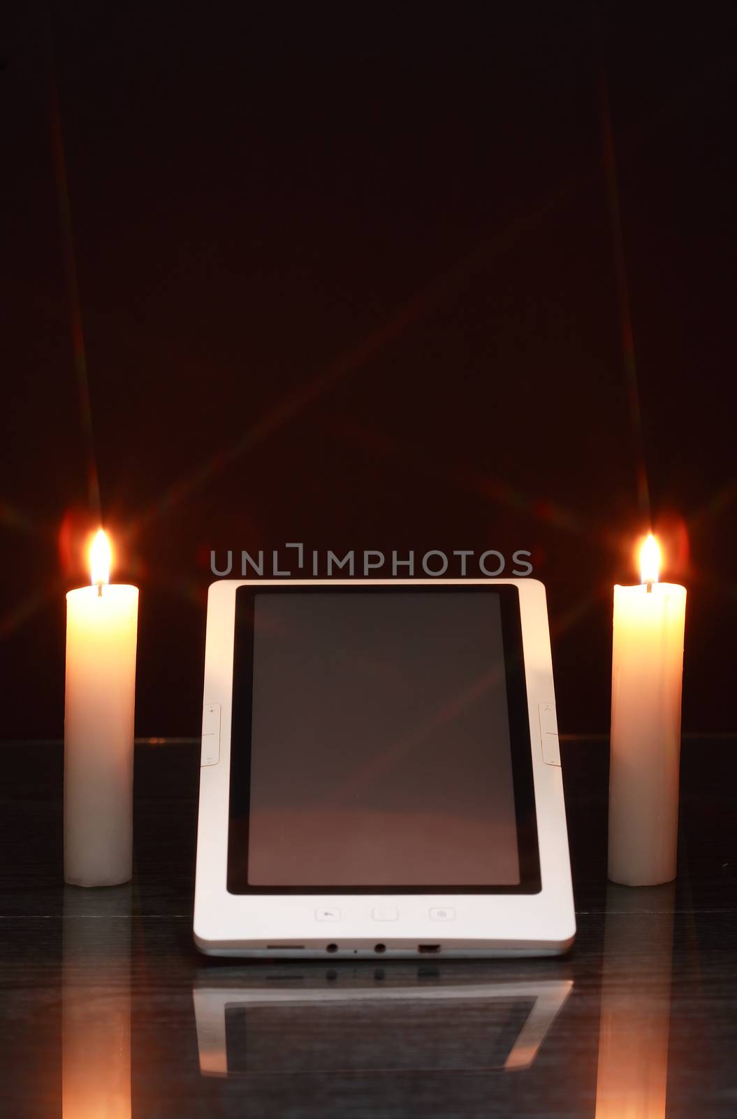 Blackout concept. Lighting candles around tablet like a sanctuary