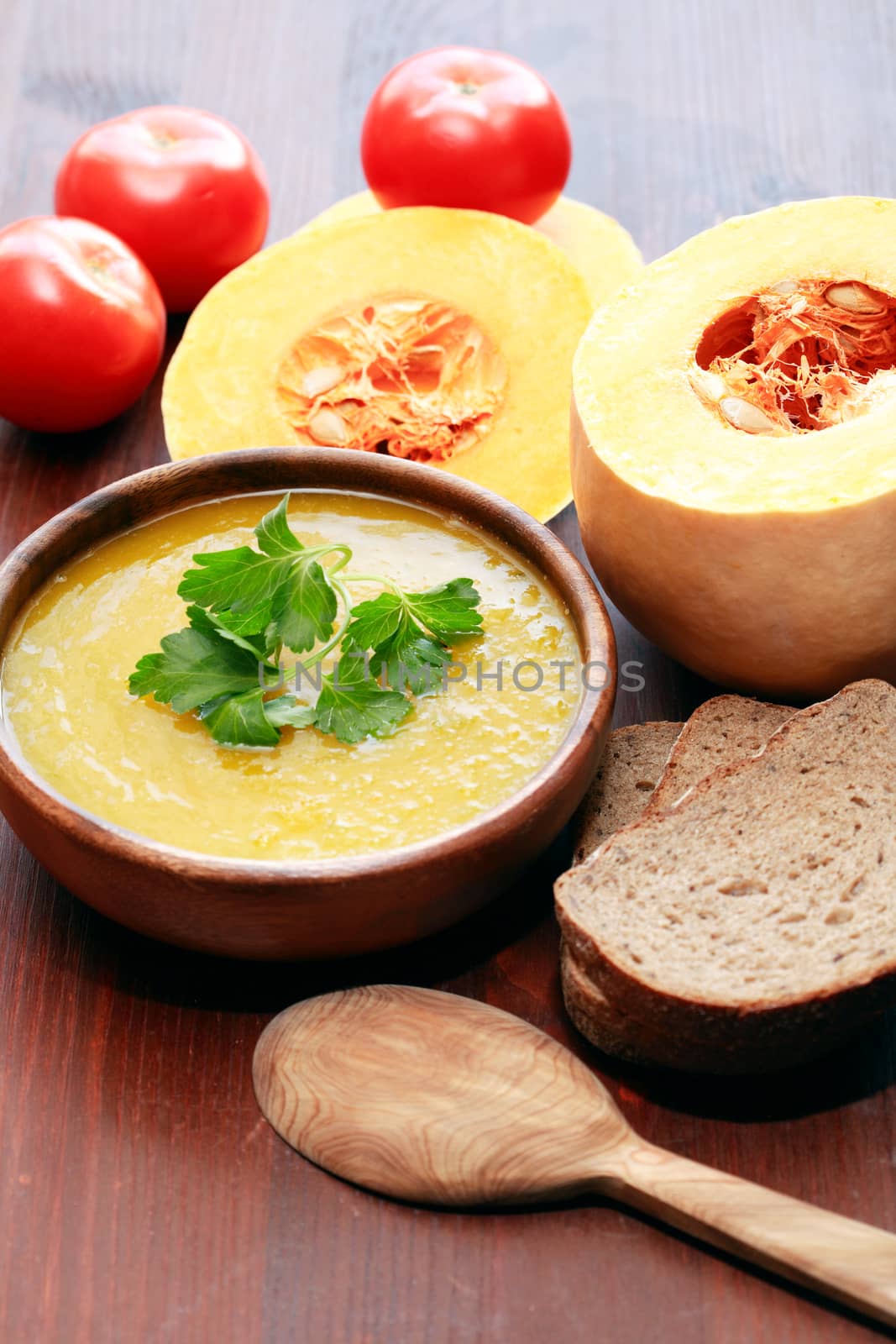 Nice wooden bowl with pumpkin soup near vegetables