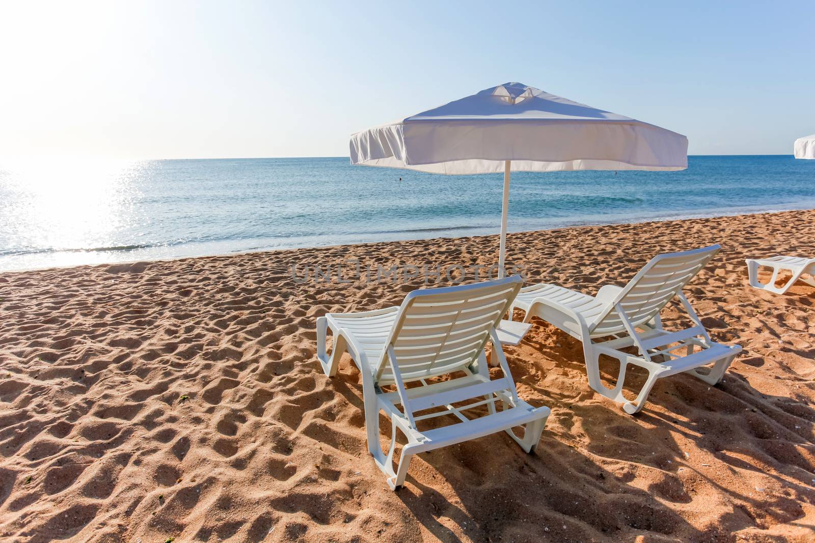 Sunbeds and sun umbrellas on the beach of sea.