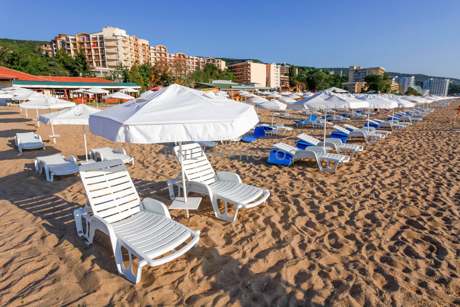 Sunbeds and sun umbrellas on the beach of sea.