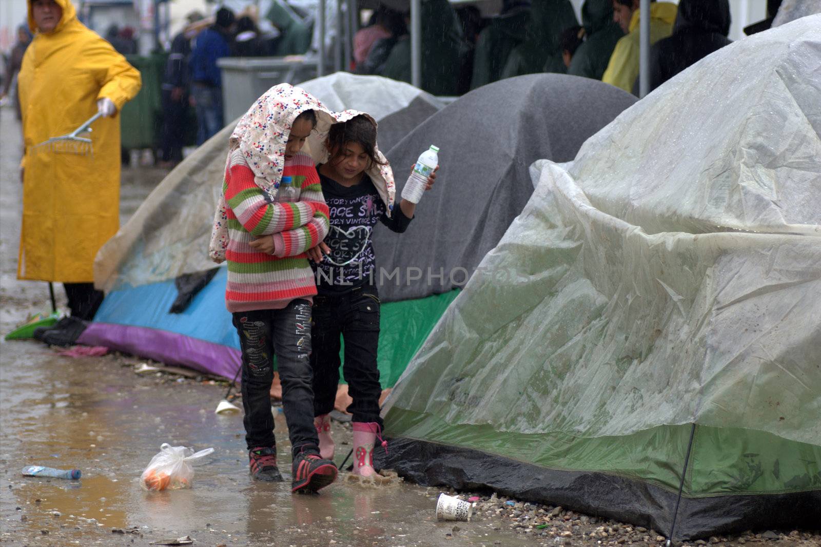 GREECE, Idomeni: Two girls walk in mud as thousands of migrants are stranded in a makeshift camp for migrants and refugees at the Greek-Macedonian border near the village of Idomeni on March 23, 2016. The UN refugee agency harshly criticized an EU-Turkey deal on curbing the influx of migrants to Greece, saying reception centers had become detention facilities, and suspended some activities in the country. The EU and Ankara struck a deal aiming to cut off the sea crossing from Turkey to the Greek islands that enabled 850,000 people to pour into Europe last year, many of them fleeing the brutal war in Syria.
