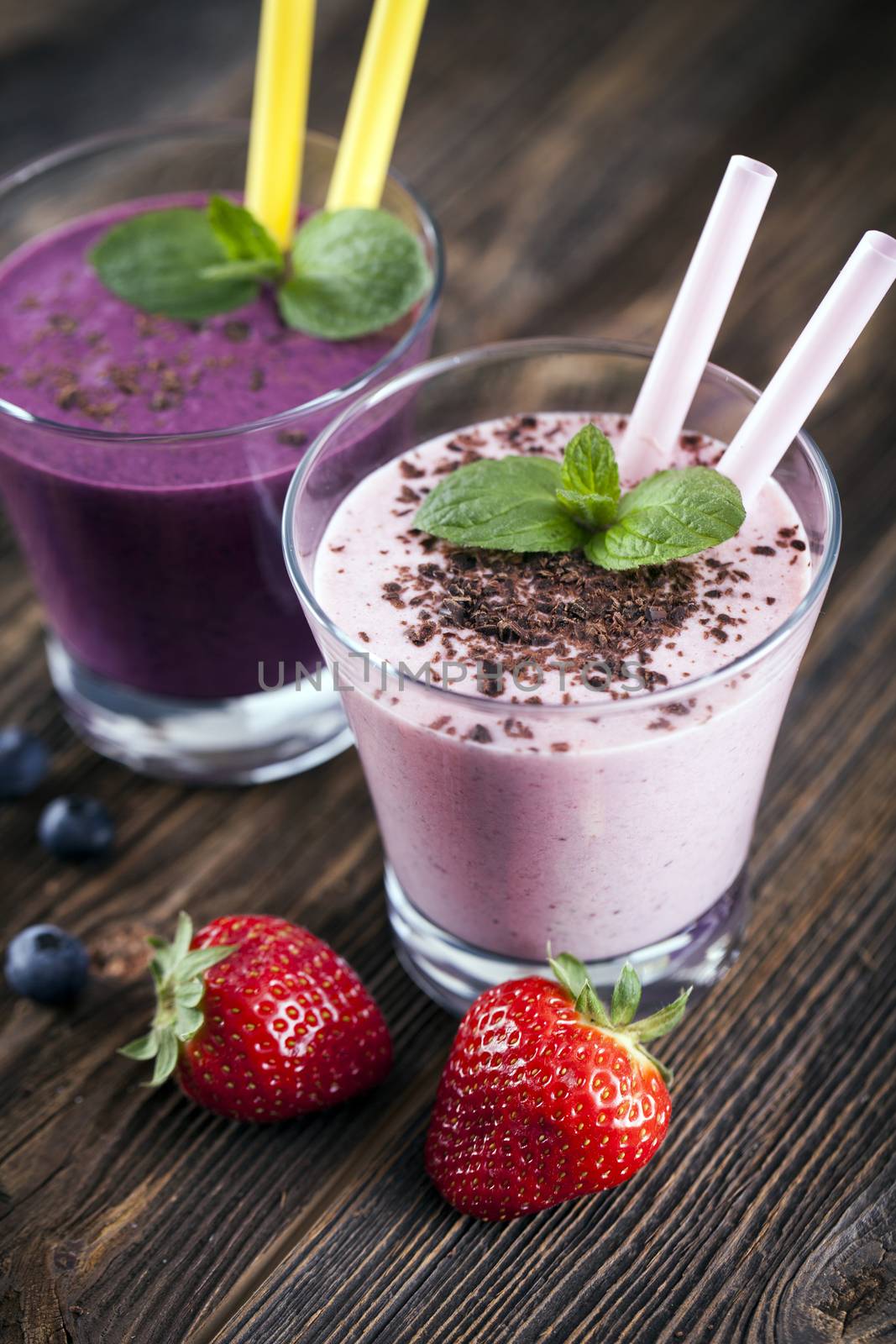 Tasty strawberry and blueberry shake on wooden table with fruits