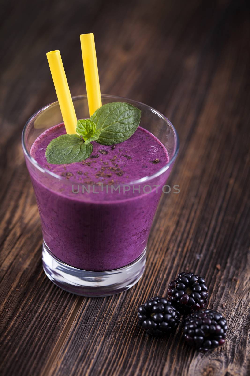 Tasty blueberry shake on wooden table with fruits