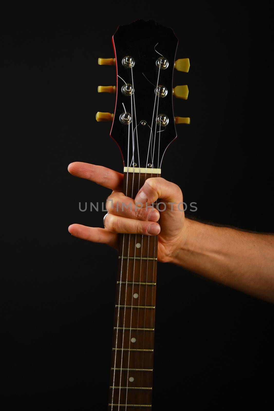 Hand with guitar and devil horns isolated on black by BreakingTheWalls