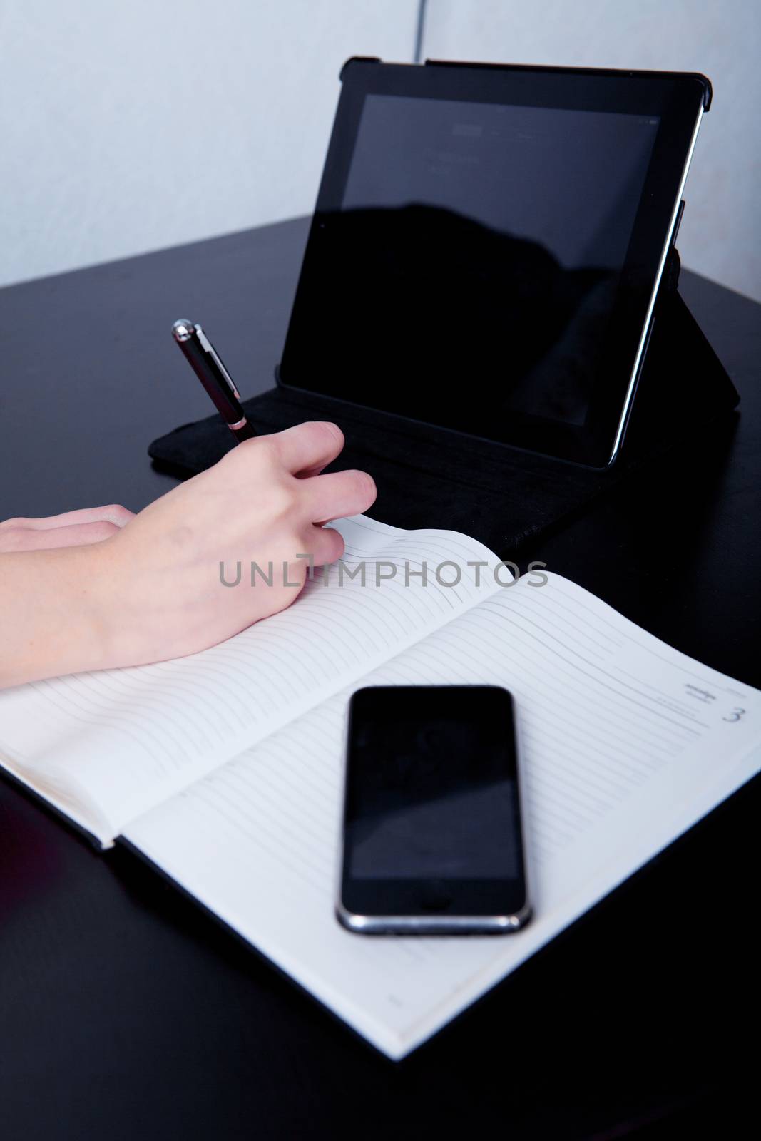 business woman in a cafe making notes in a diary, on the background of the phone and tablet