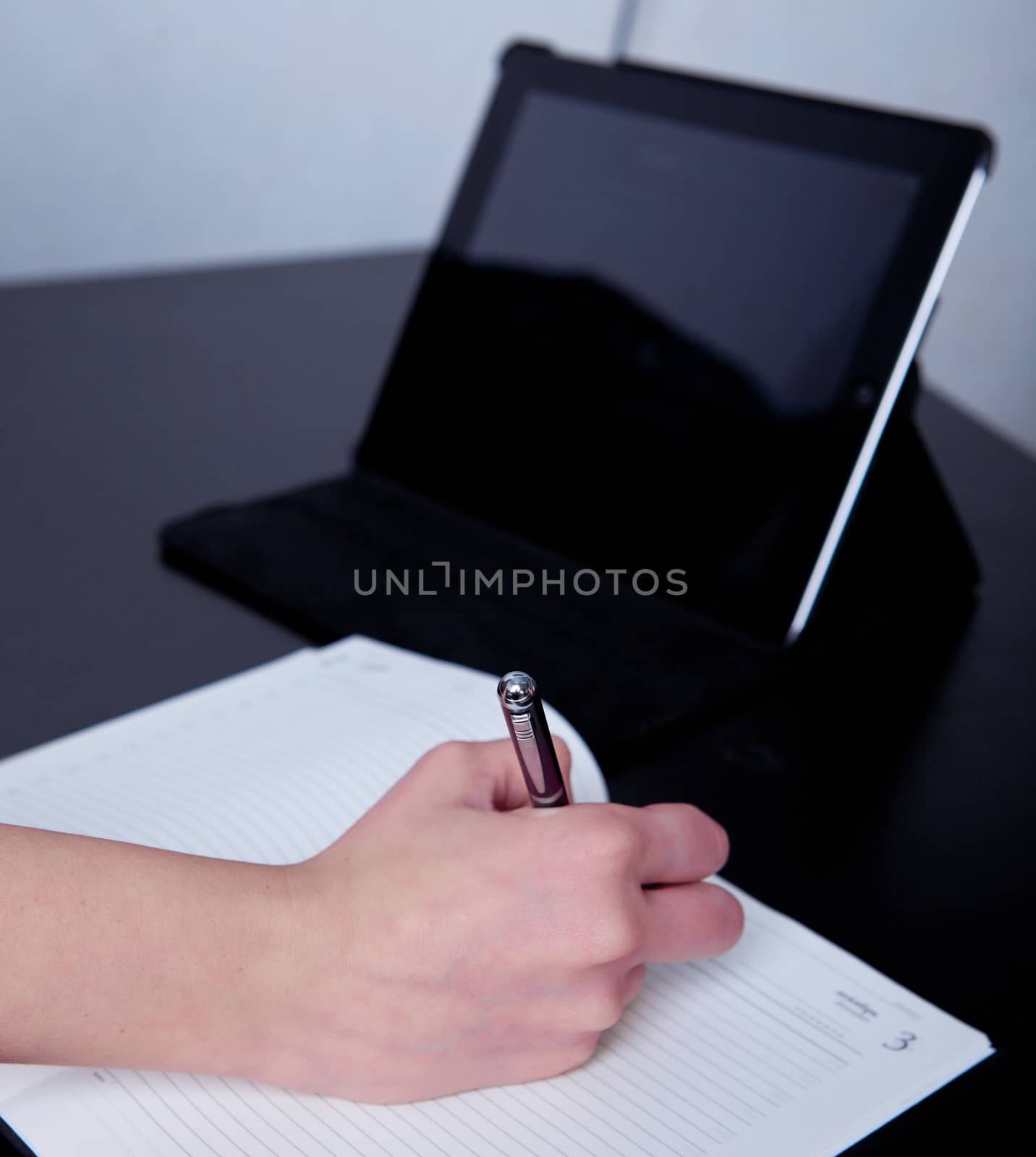 business woman in a cafe making notes in a diary, on the background of the phone and tablet